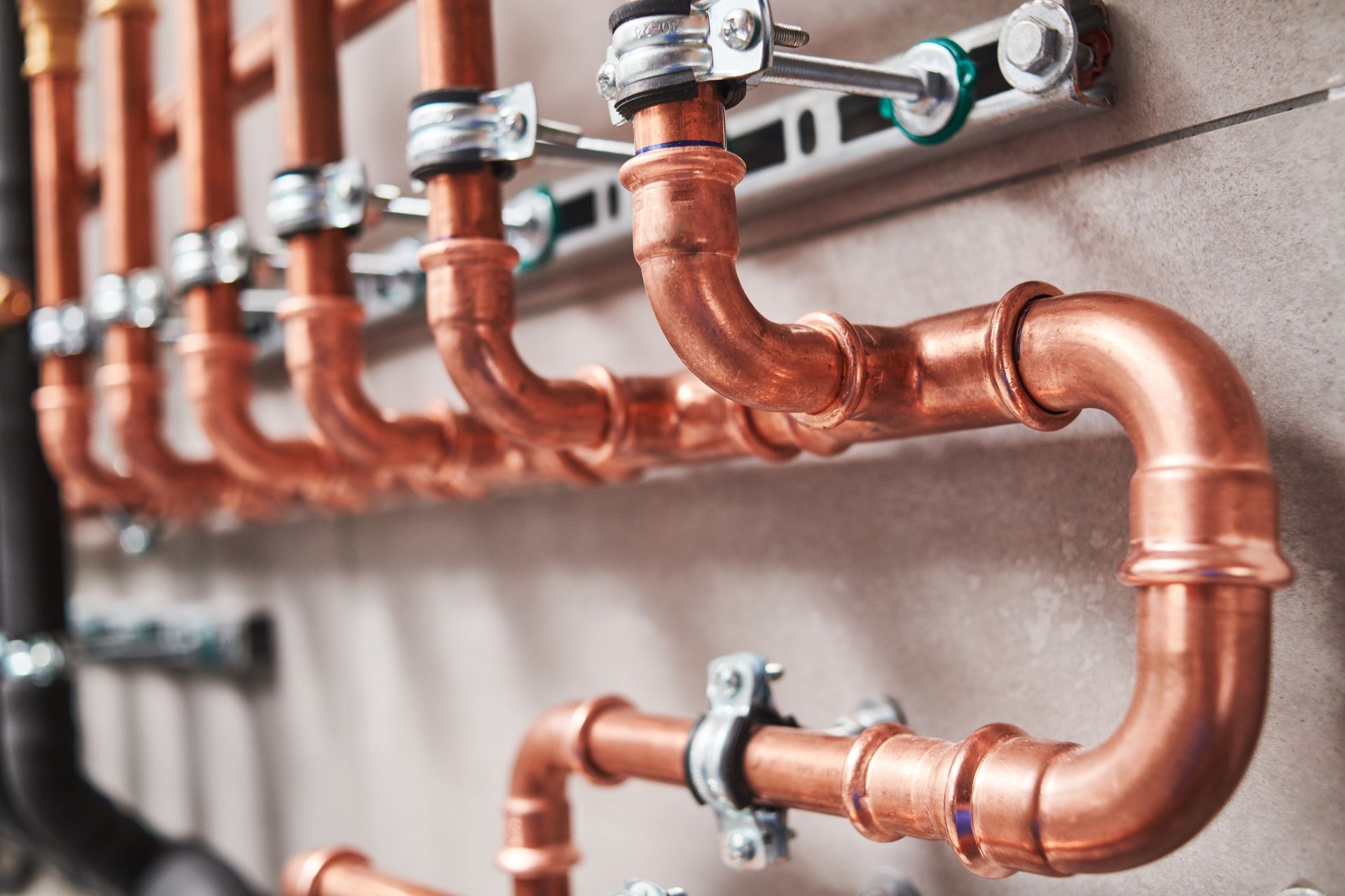 Copper pipes with valves and fittings mounted on a wall in a plumbing system