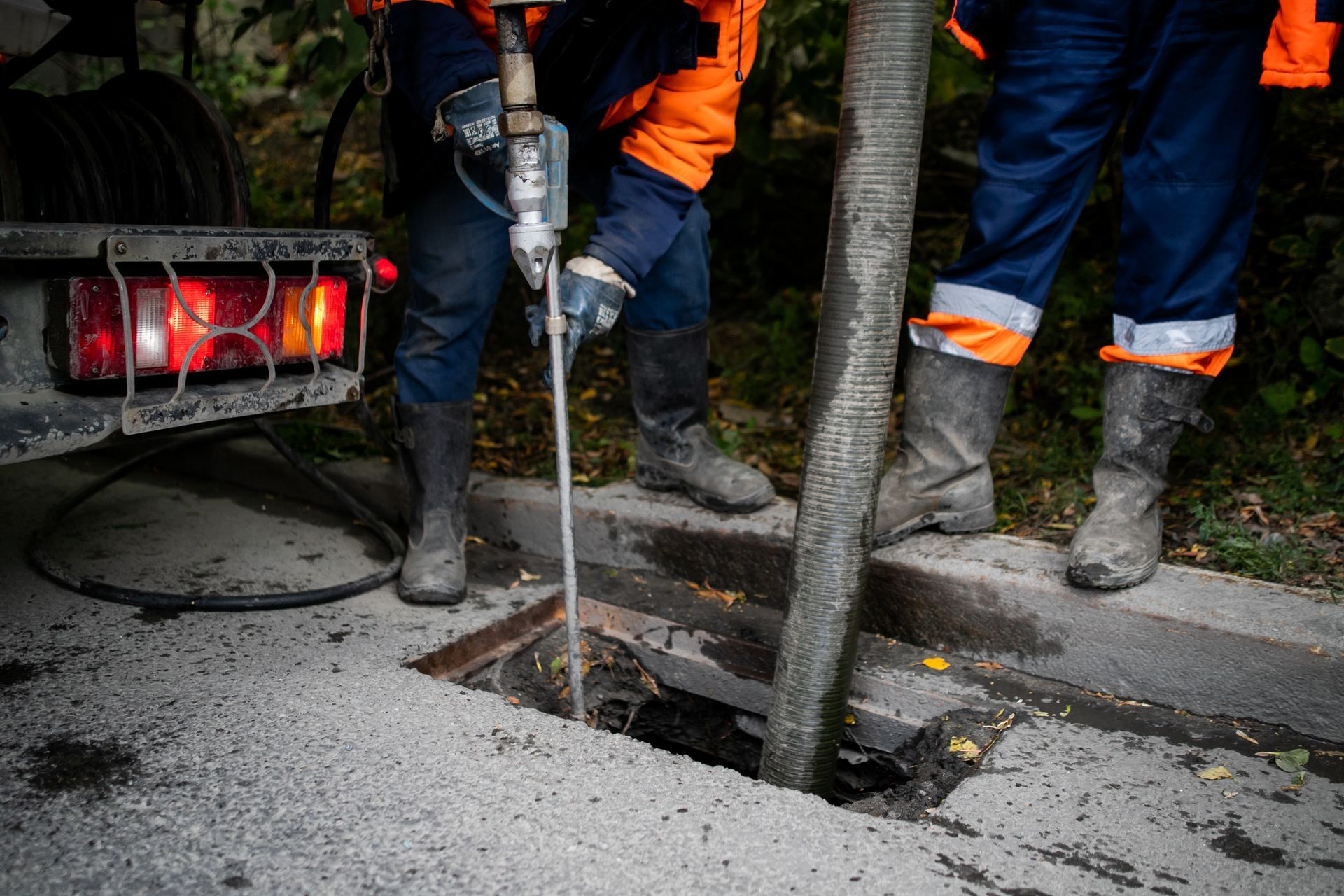 Workers drilling a sidewalk hole beside a tree at a street construction site