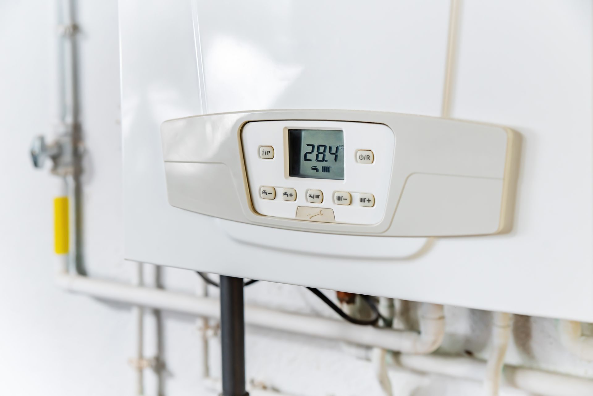 Wall-mounted boiler control panel with digital temperature display in a white utility room