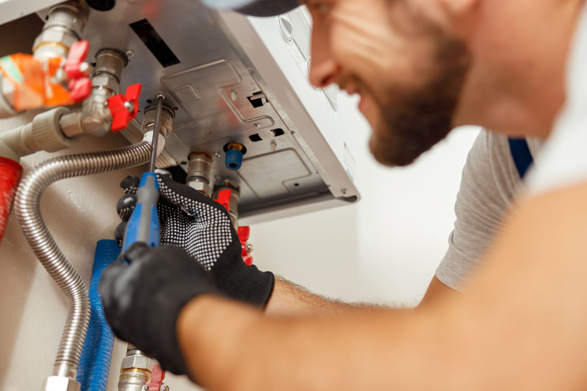Plumber repairing pipes under a sink with tools and exposed plumbing lines
