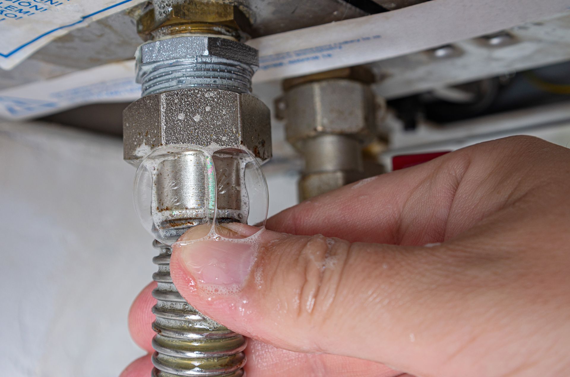 Hand tightening a metal hose connector under a sink