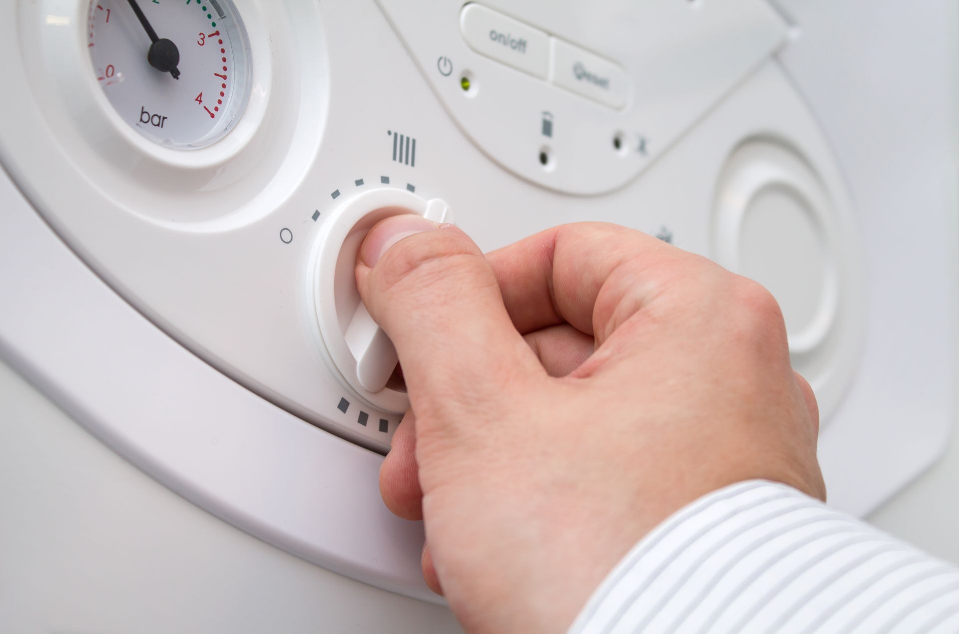 Hand adjusting a white washing machine dial with a towel visible