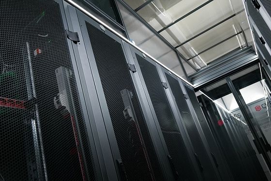 Une rangée de grandes baies de serveurs noires et perforées dans un centre de données.