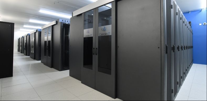 Des rangées de hautes armoires serveurs noires à portes vitrées sont disposées dans une salle de centre de données propre et lumineuse.