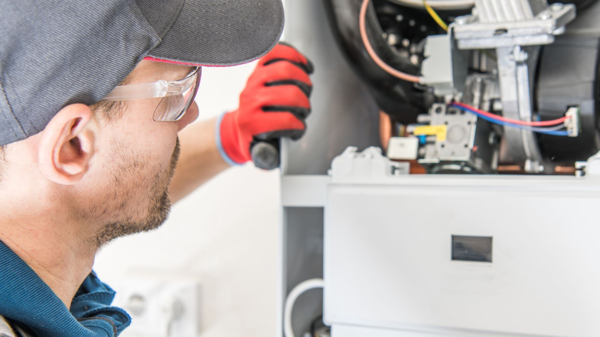 A man is working on a boiler with a flashlight.