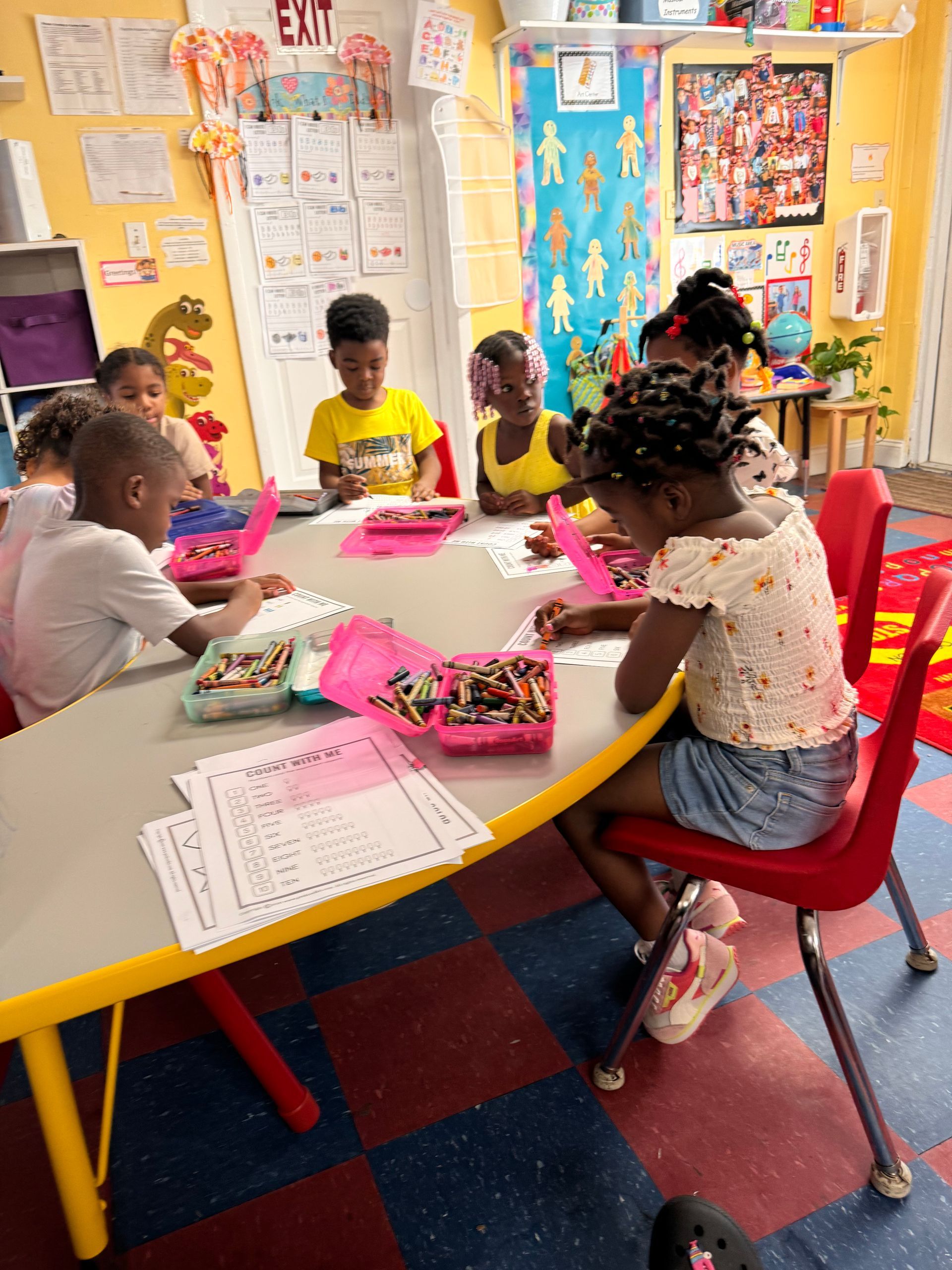 A group of children are sitting around a table with crayons.