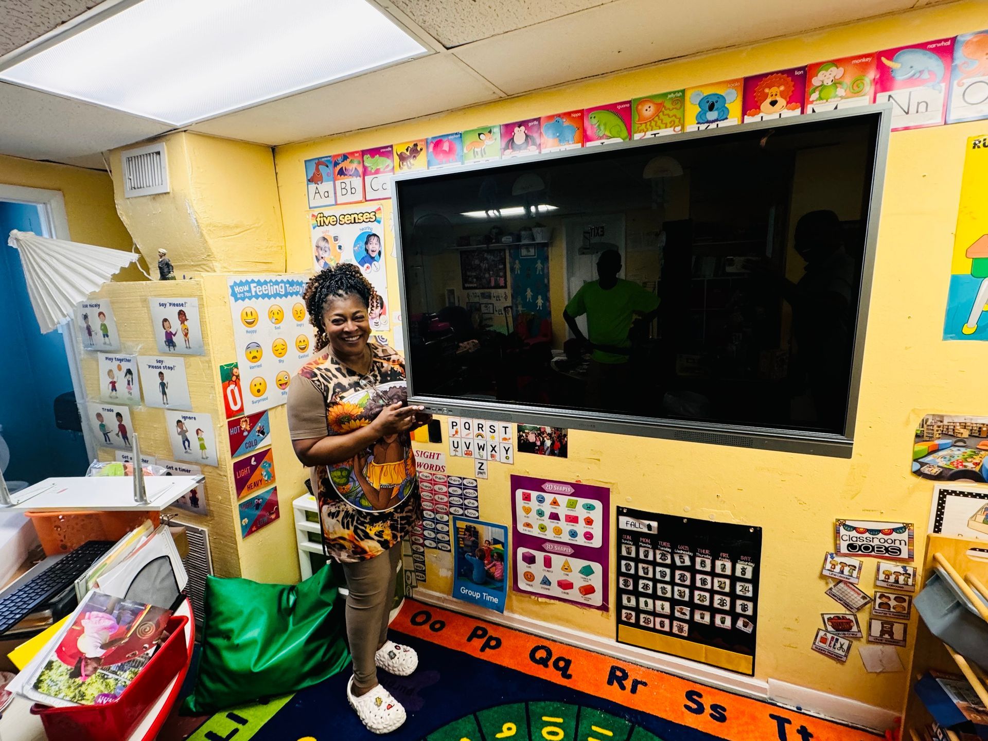 A woman is standing in front of a large screen in a classroom.