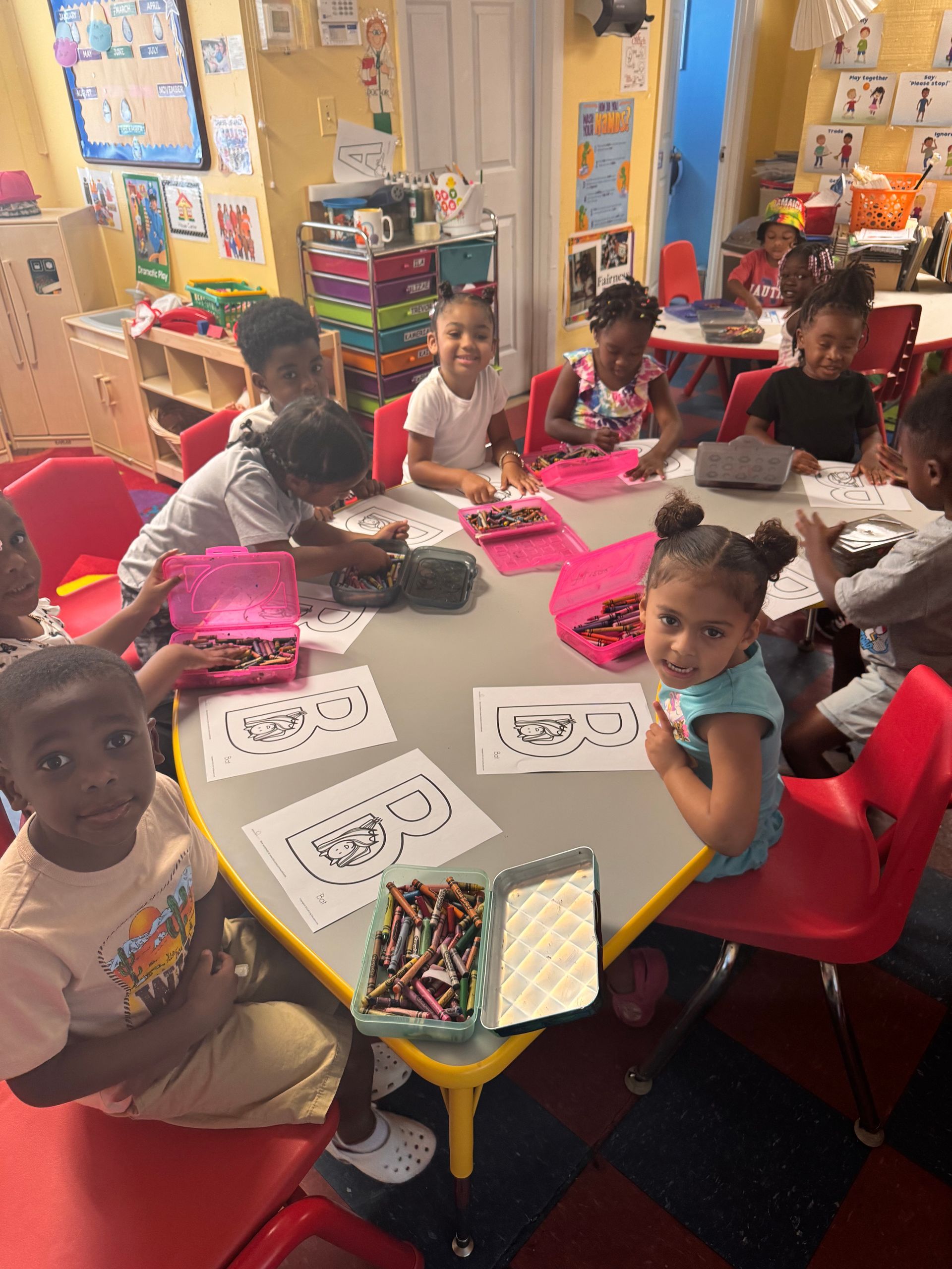 A group of children are sitting around a table in a classroom.