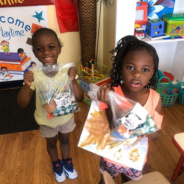 Two little girls are standing in front of a sign that says come playtime