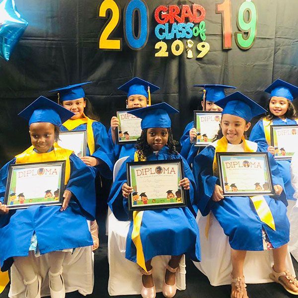 A group of children in graduation caps and gowns holding diplomas
