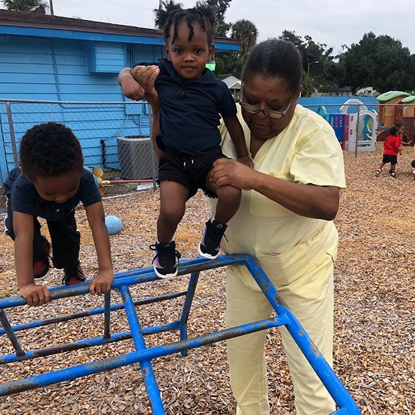 A woman is helping a child climb a monkey bars