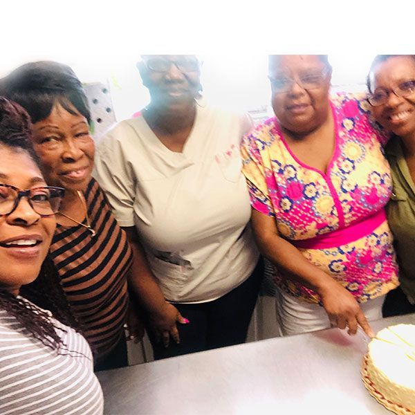 A group of women are posing for a picture in front of a cake.