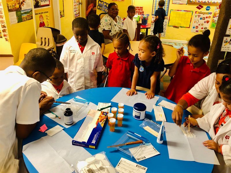 A group of children are sitting around a blue table
