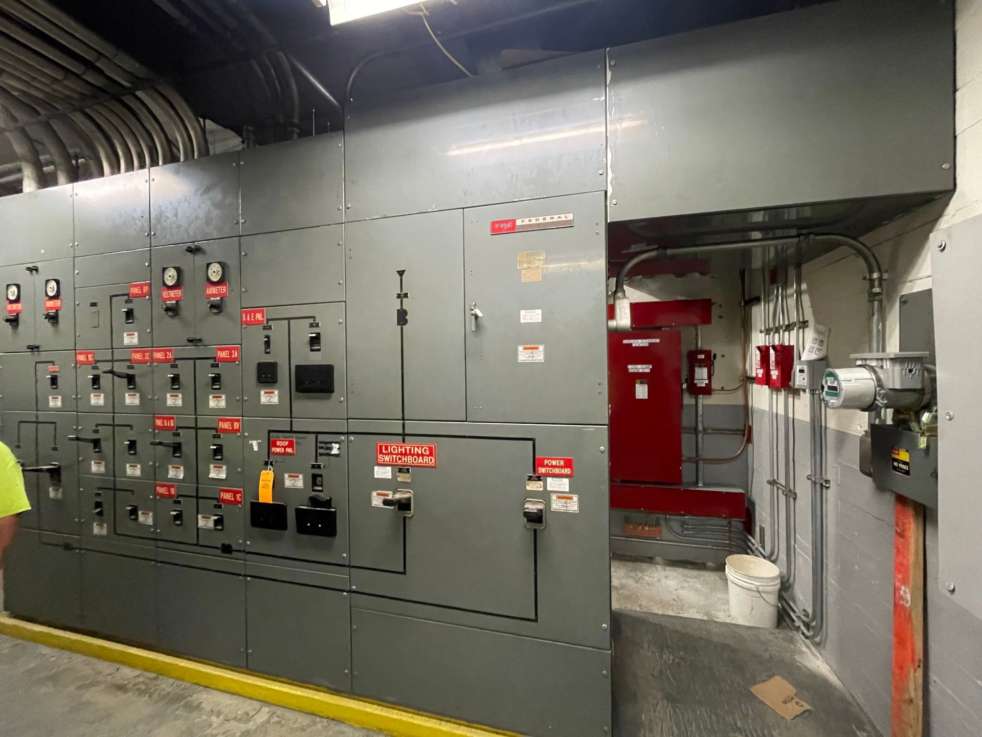 A man is standing in front of a large electrical panel in a room.