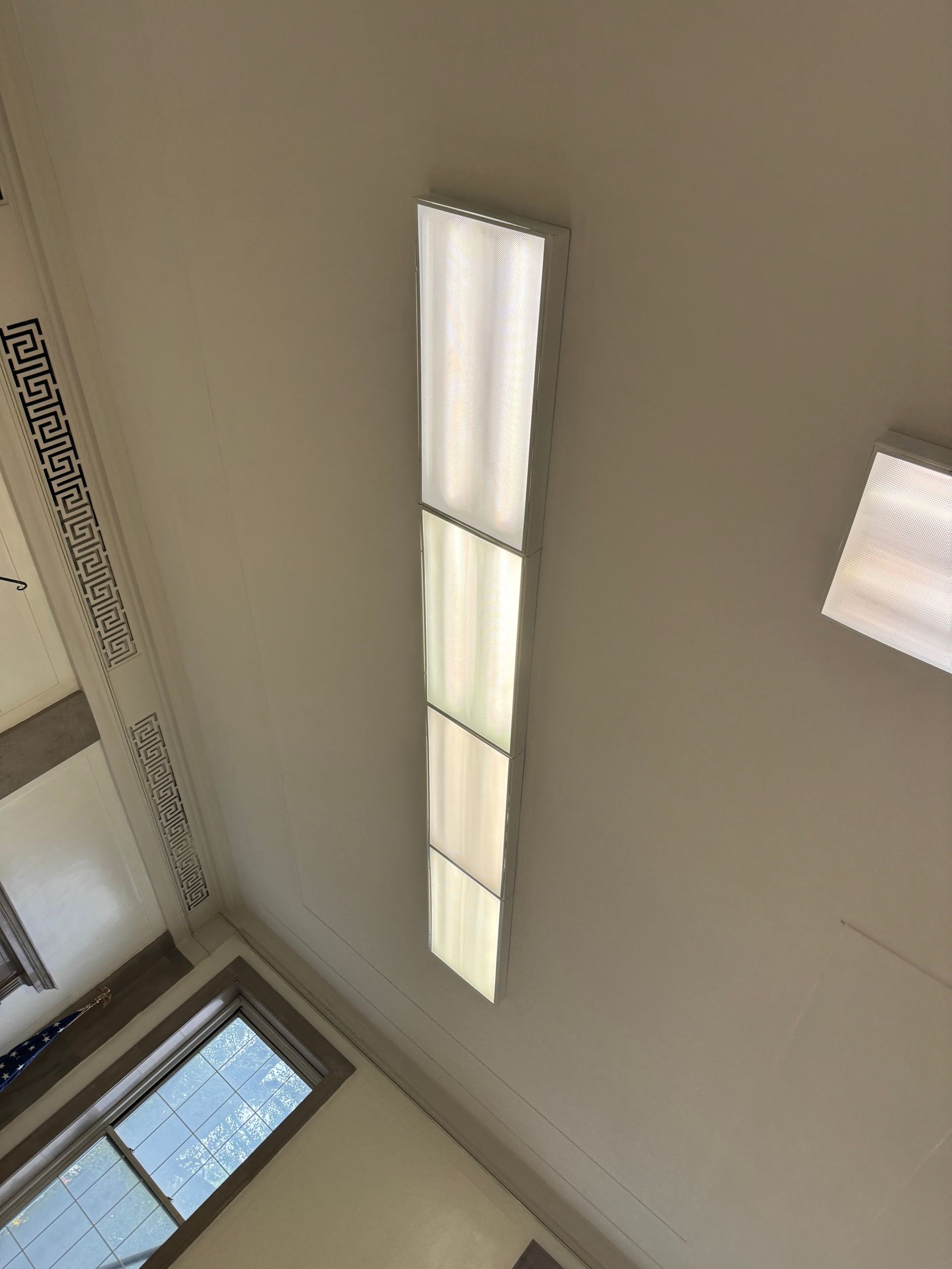 A long light fixture is hanging from the ceiling of a room.