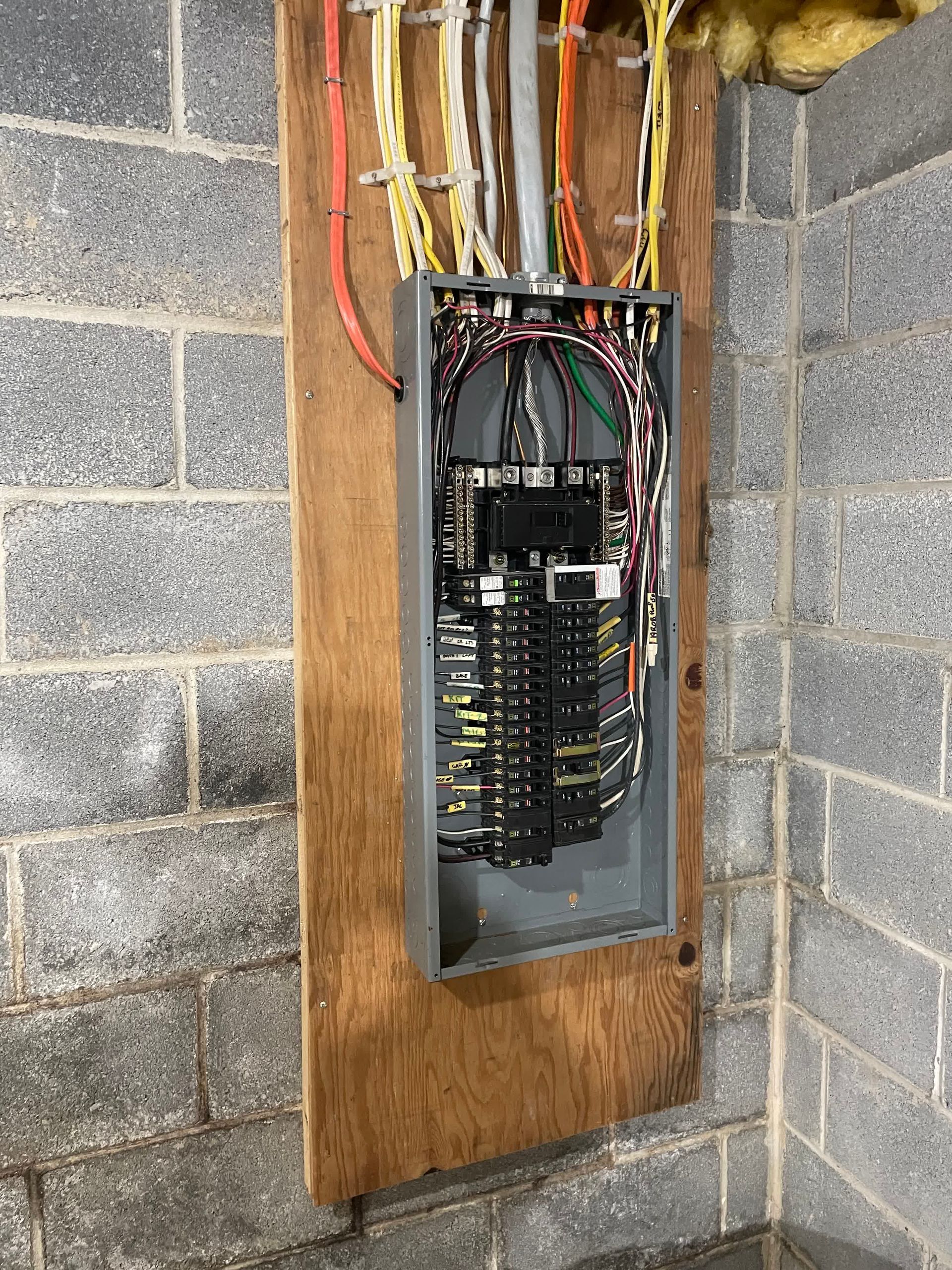 A electrical box is hanging on a brick wall.