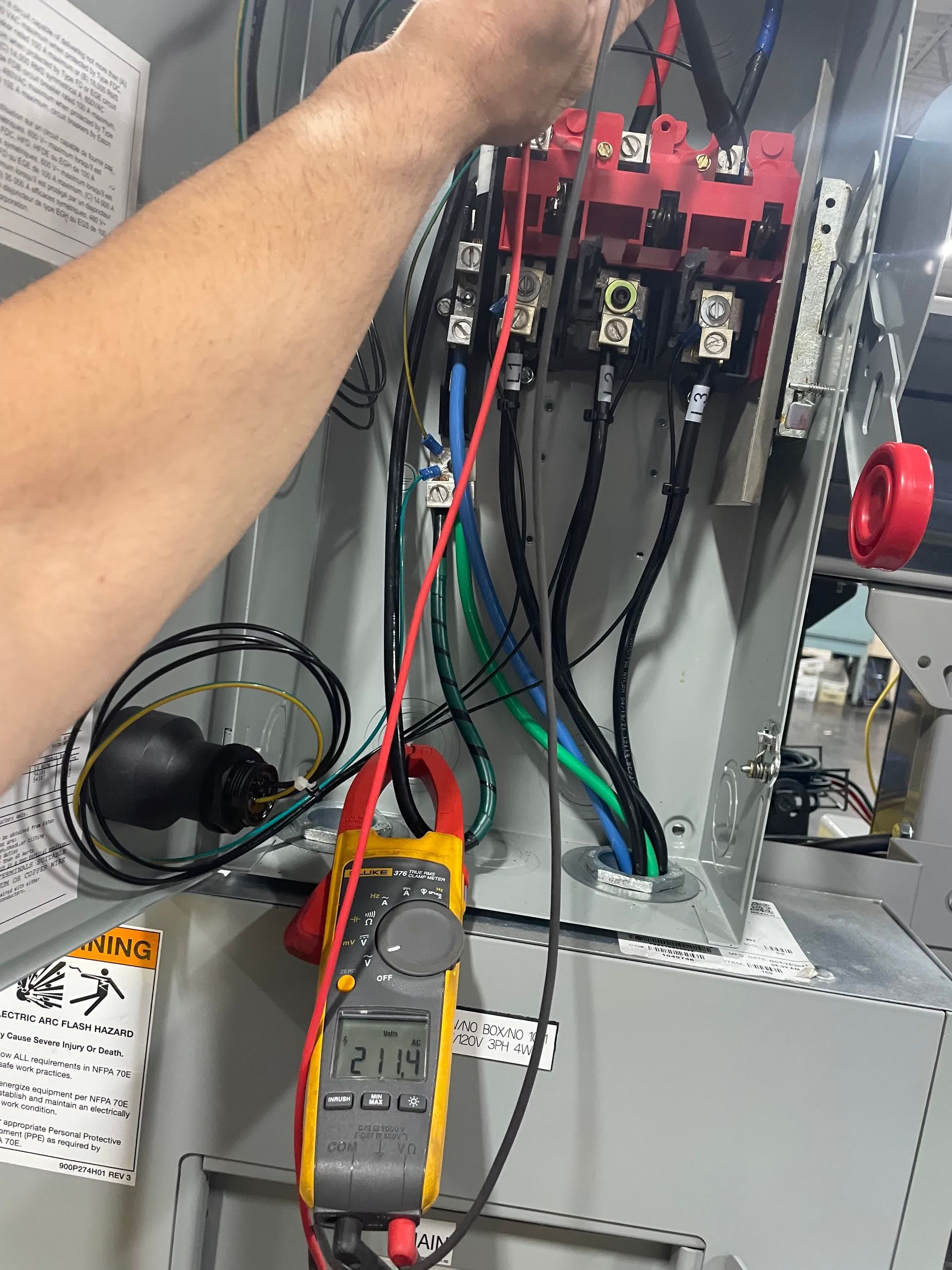 A person is working on an electrical box with a clamp meter