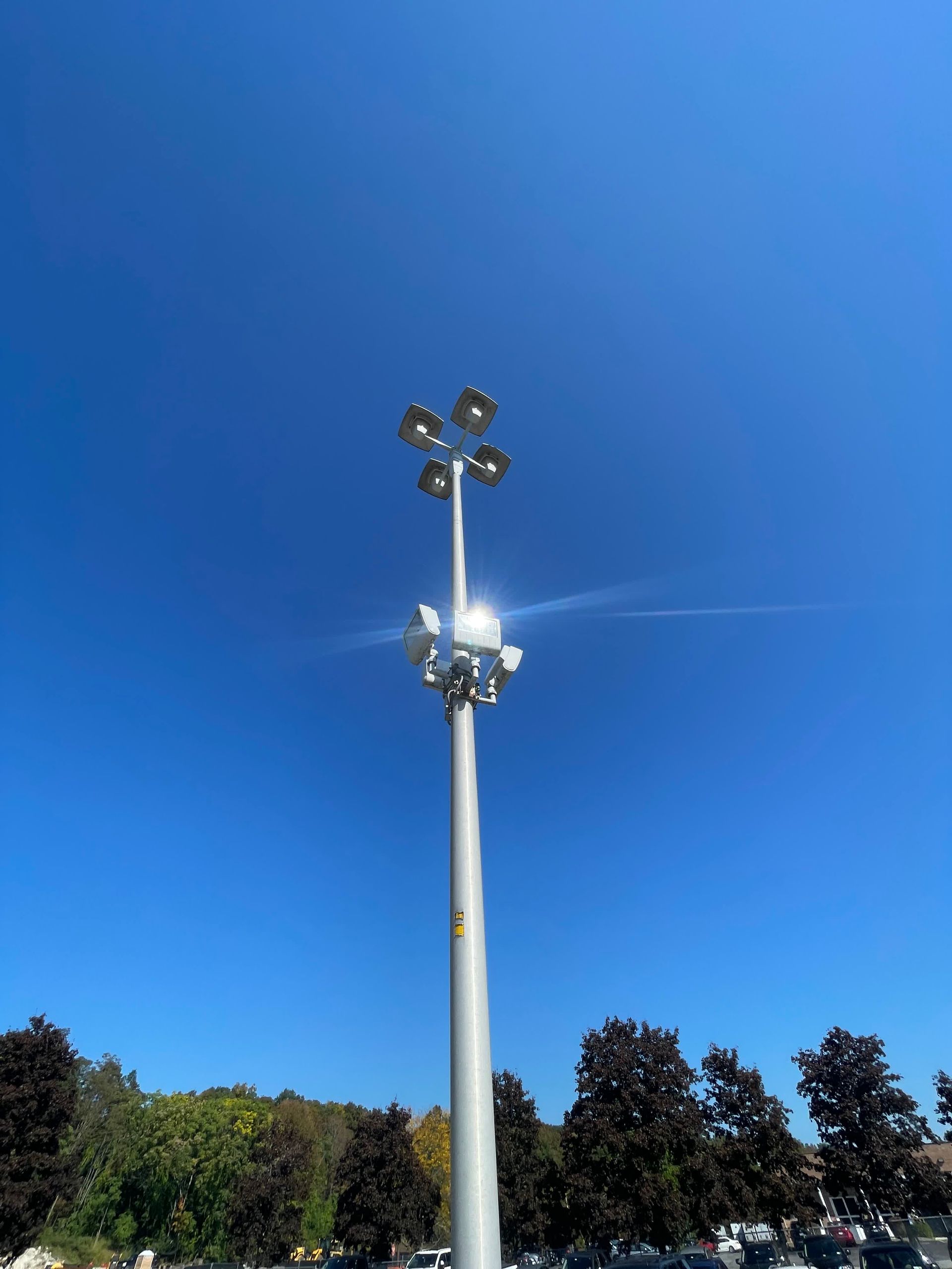 A tall pole with a lot of lights on it against a blue sky.