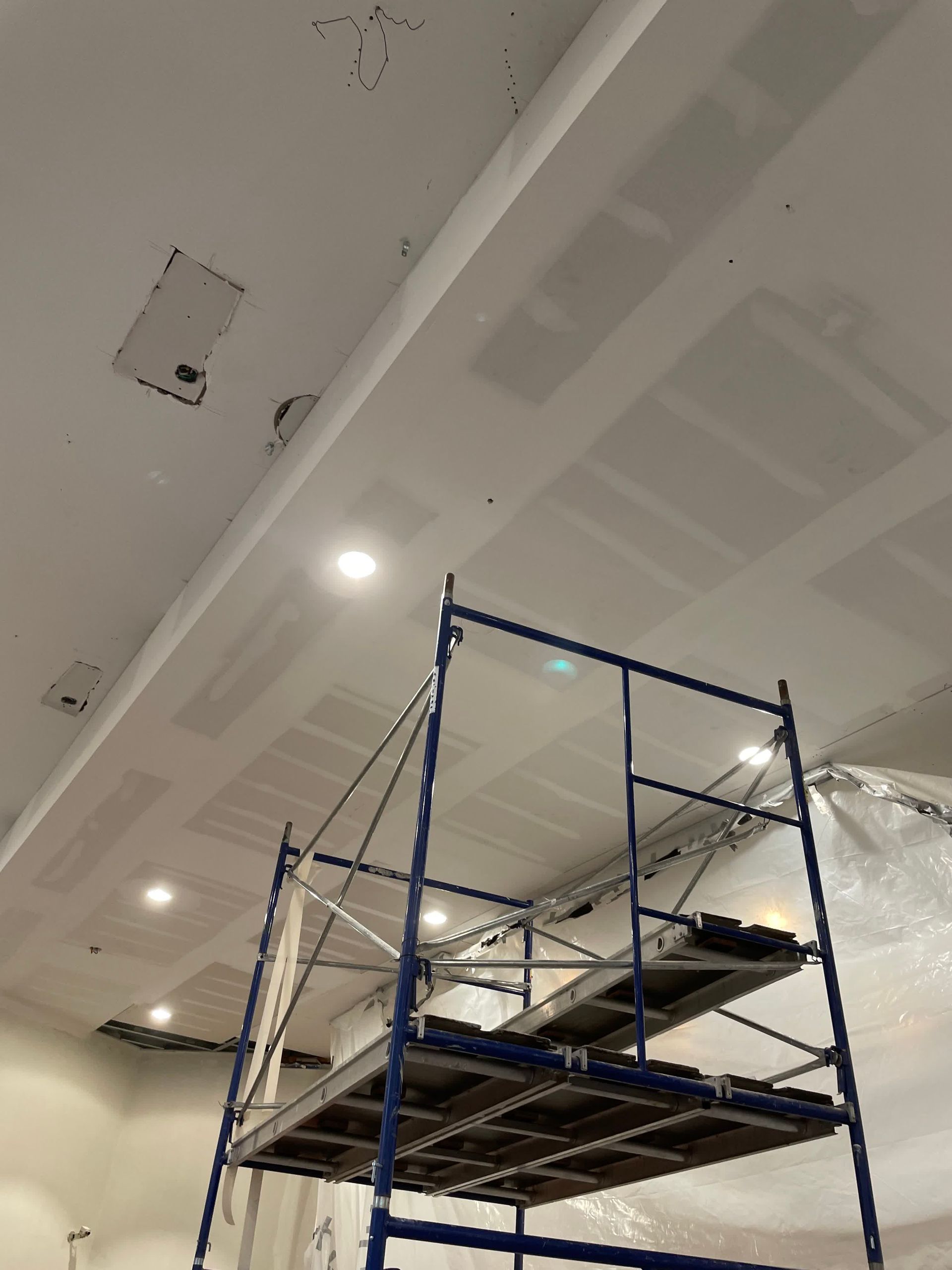 A blue scaffolding is sitting under a ceiling in a room