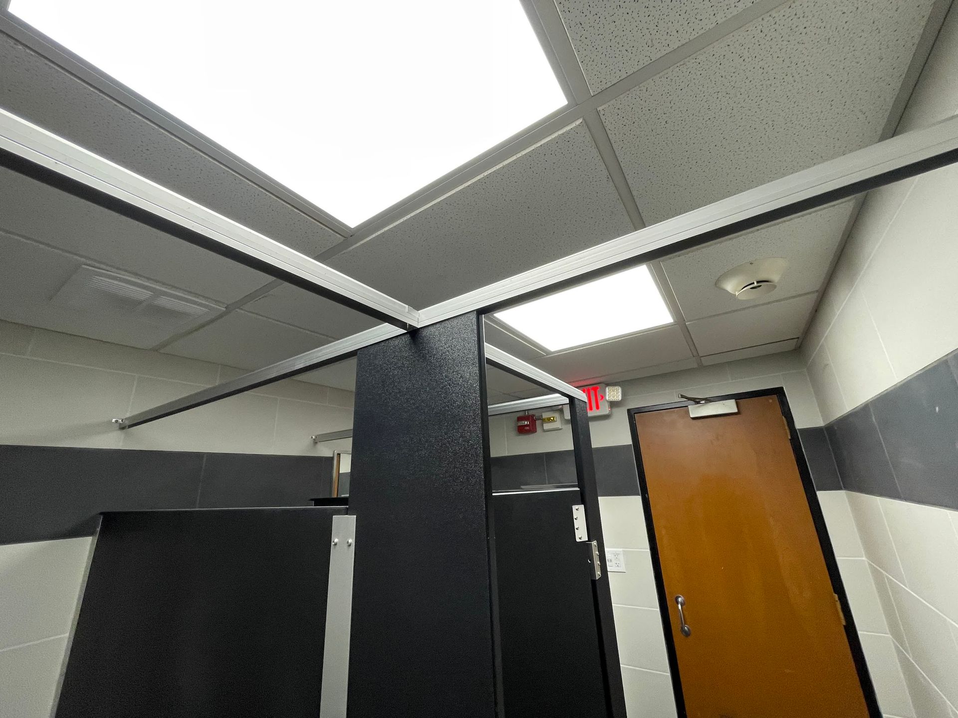 A bathroom with a red exit sign on the ceiling