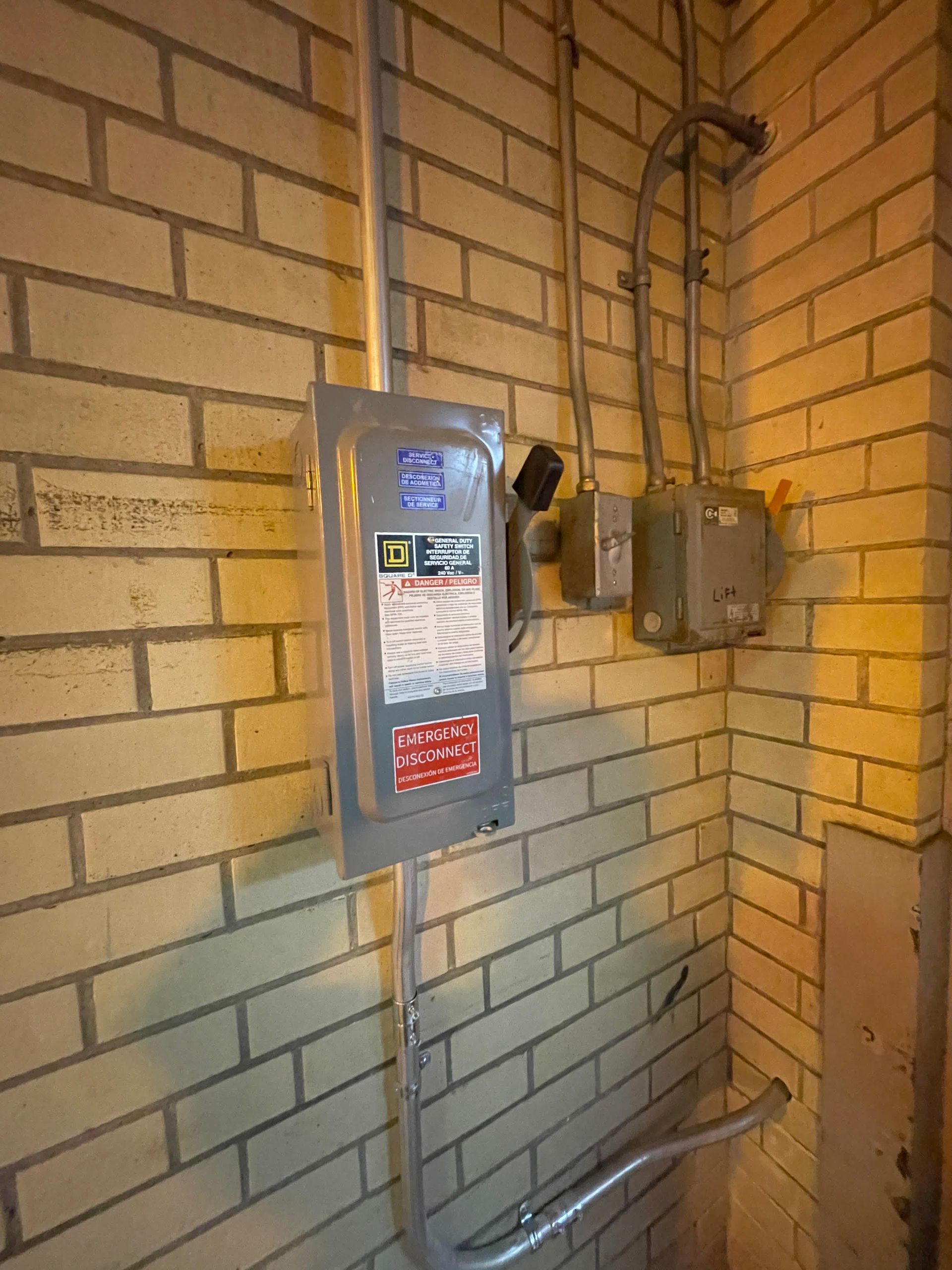 A brick wall with a electrical box on it.