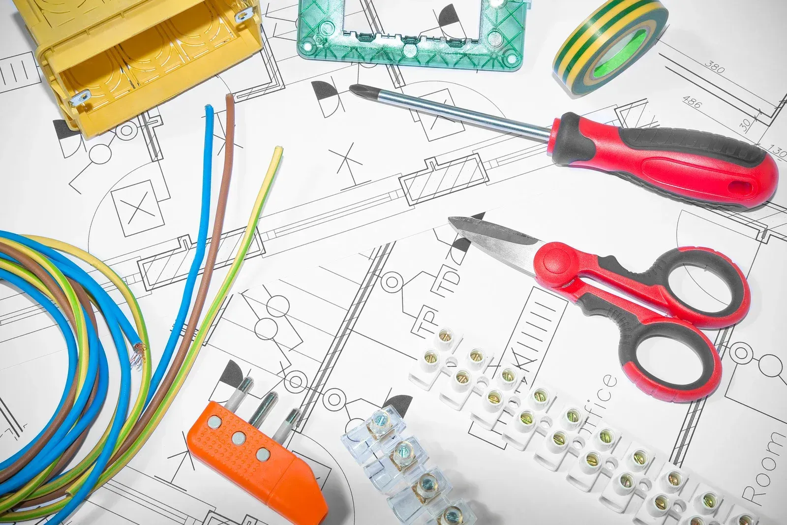 A man is working on electrical wires in a building under construction.