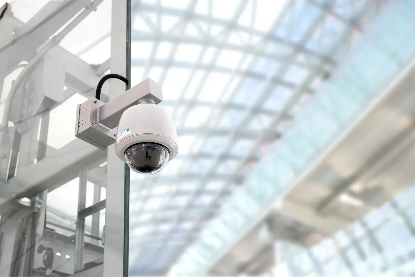 A security camera is hanging from the ceiling of a building.
