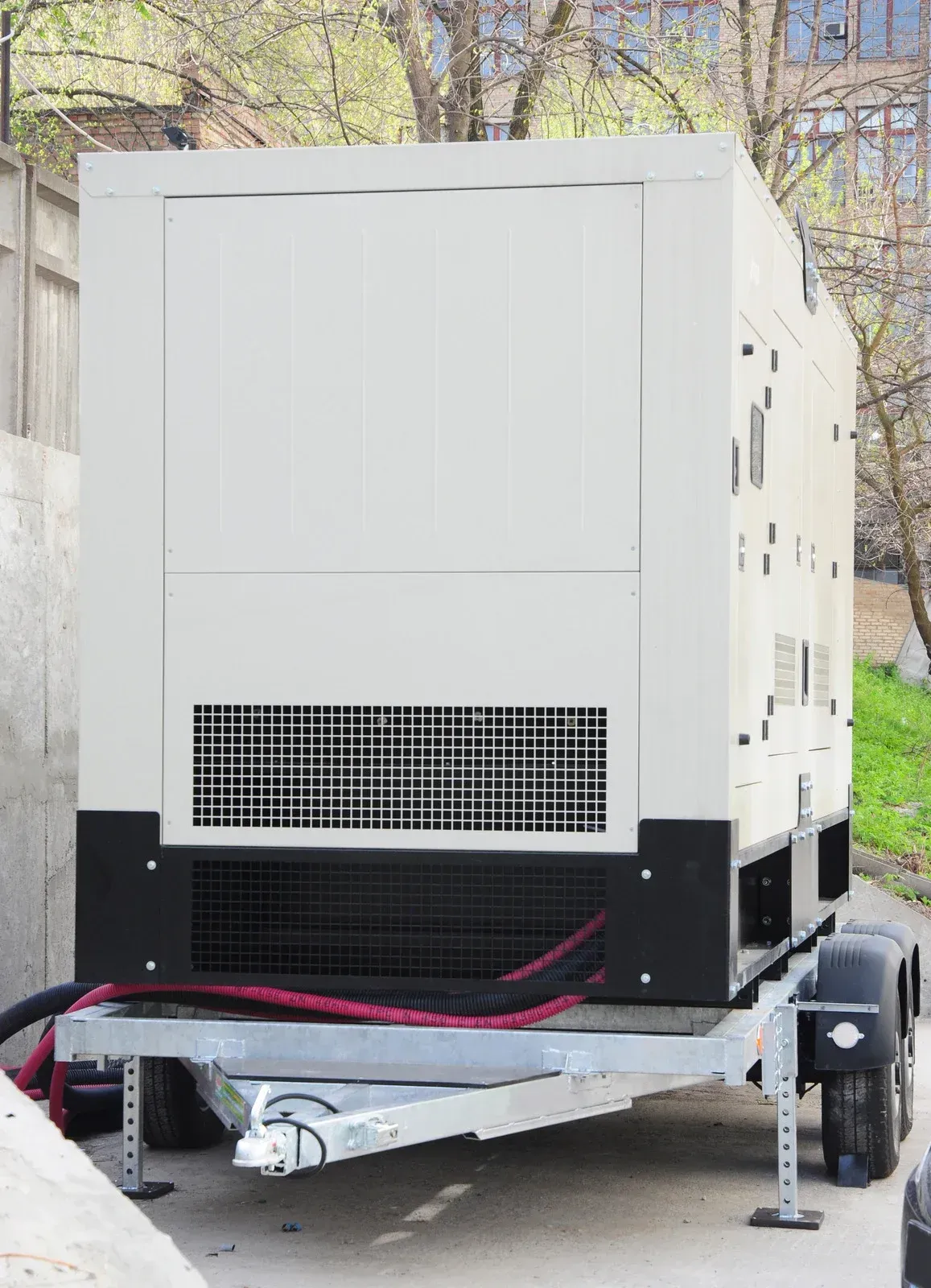 A generator is sitting on a trailer in a parking lot.