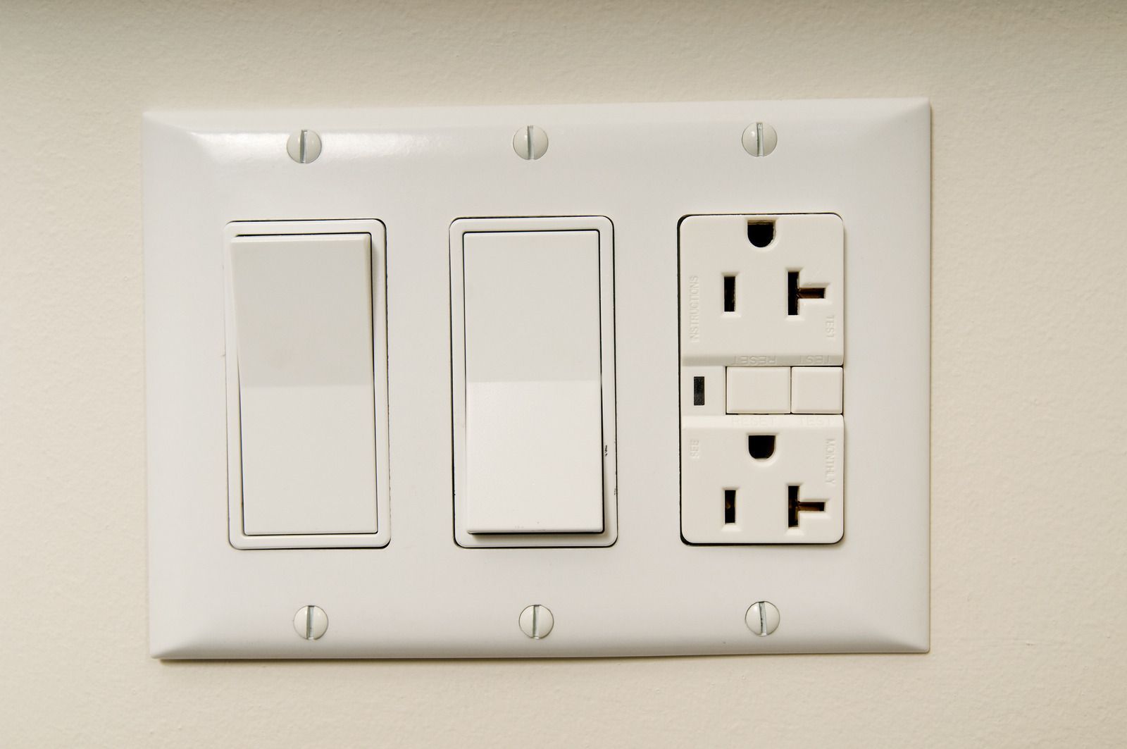 A white light switch and electrical outlet on a wall