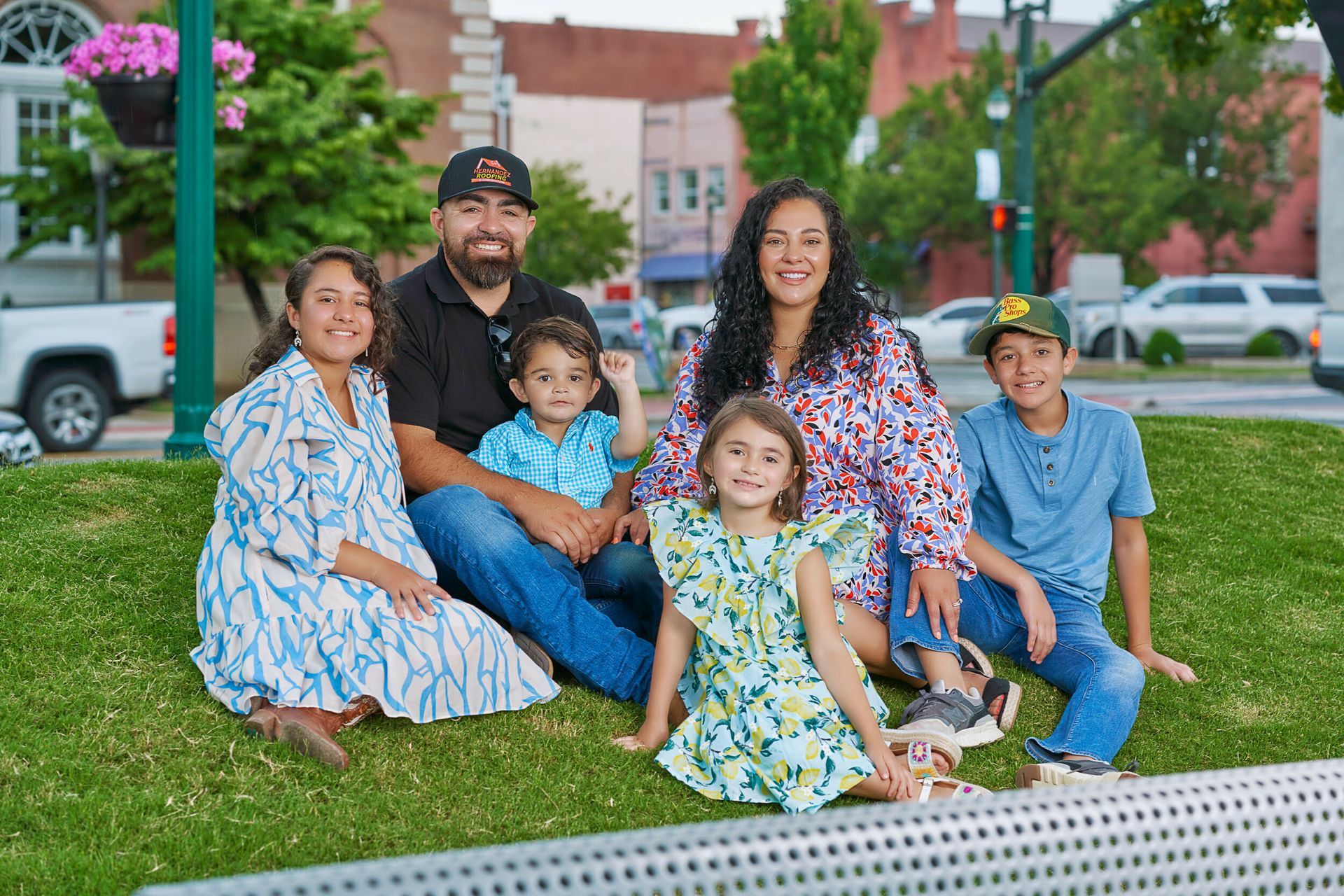 A family is sitting on the grass in a park.