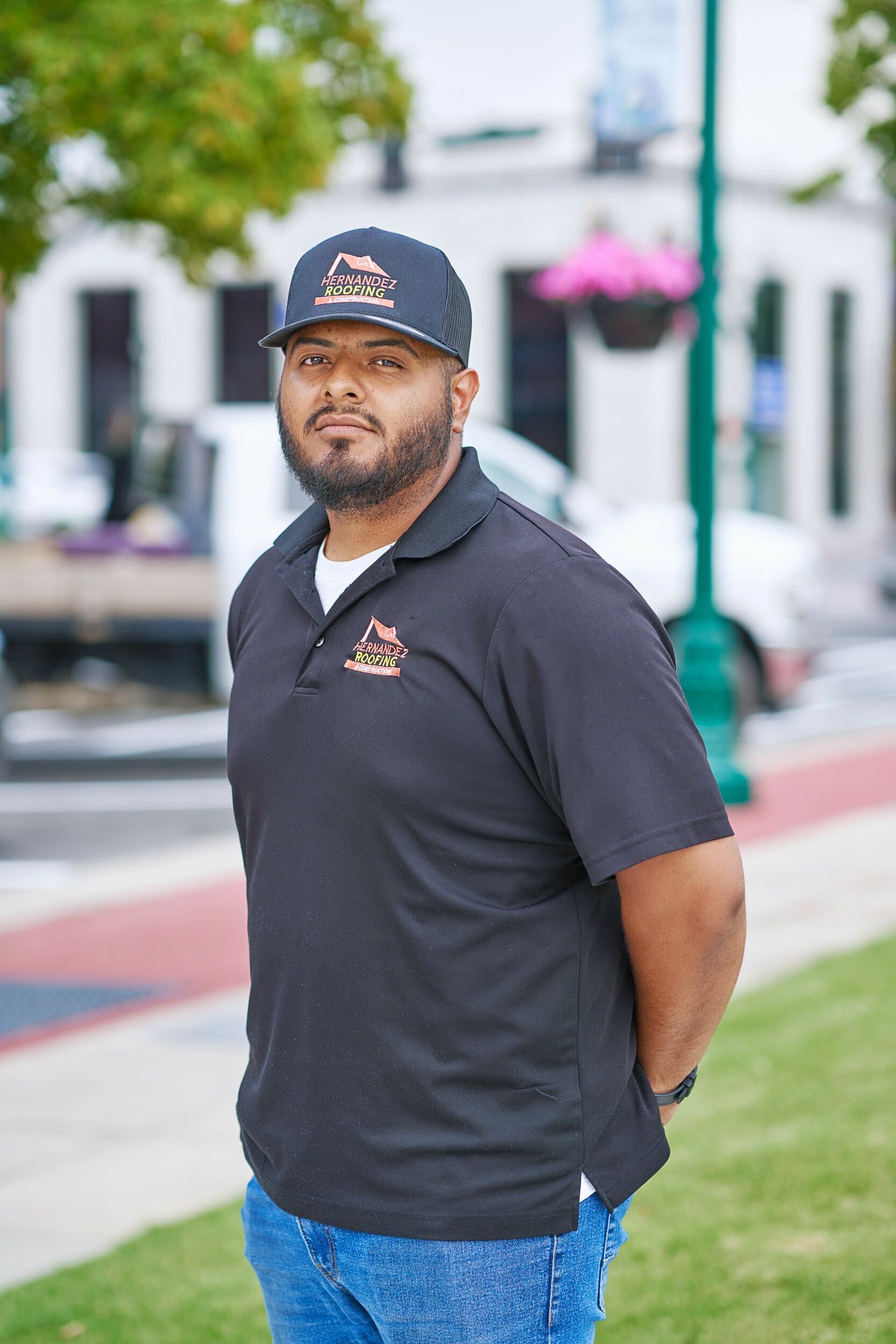 A man wearing a hat and a black shirt is standing in a park.