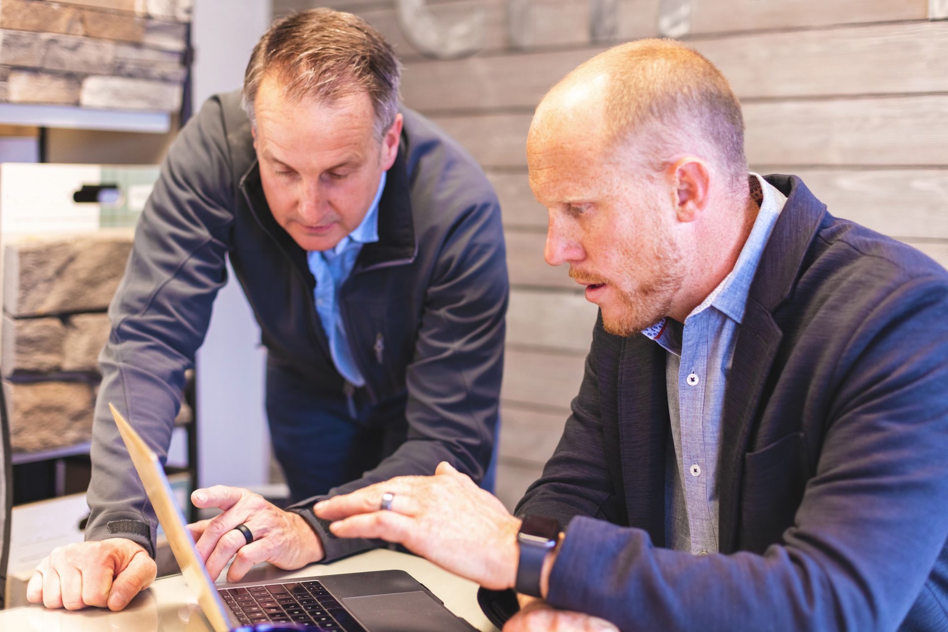 Two men are looking at a laptop computer together.