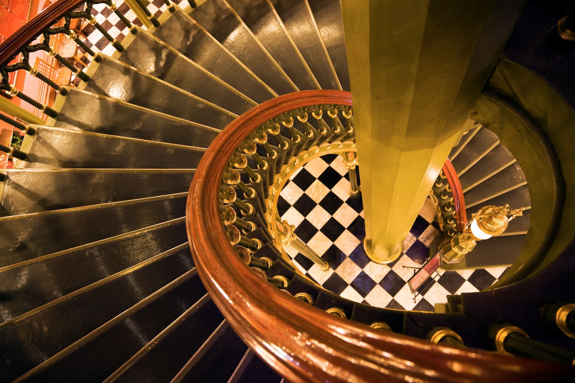 Looking down a spiral staircase with a checkered floor