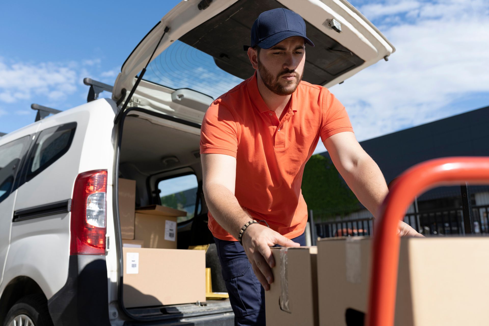 A delivery man is loading boxes into the back of a van.