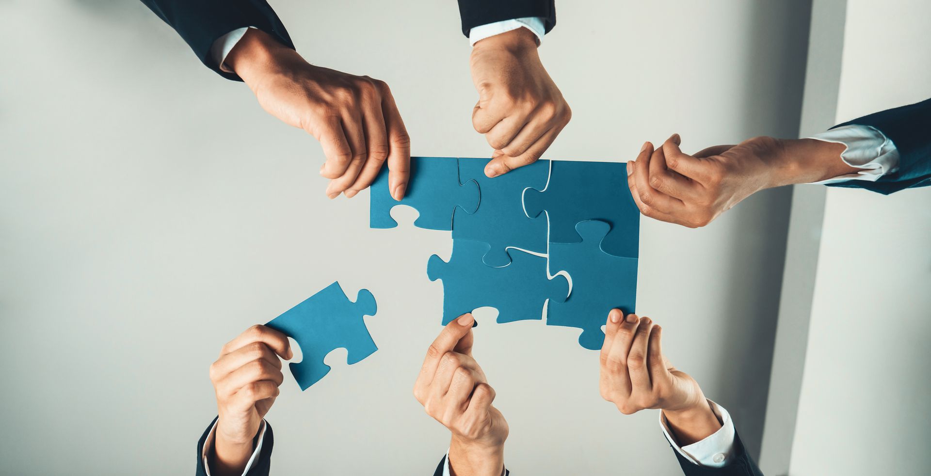 A group of people are holding blue puzzle pieces in their hands.