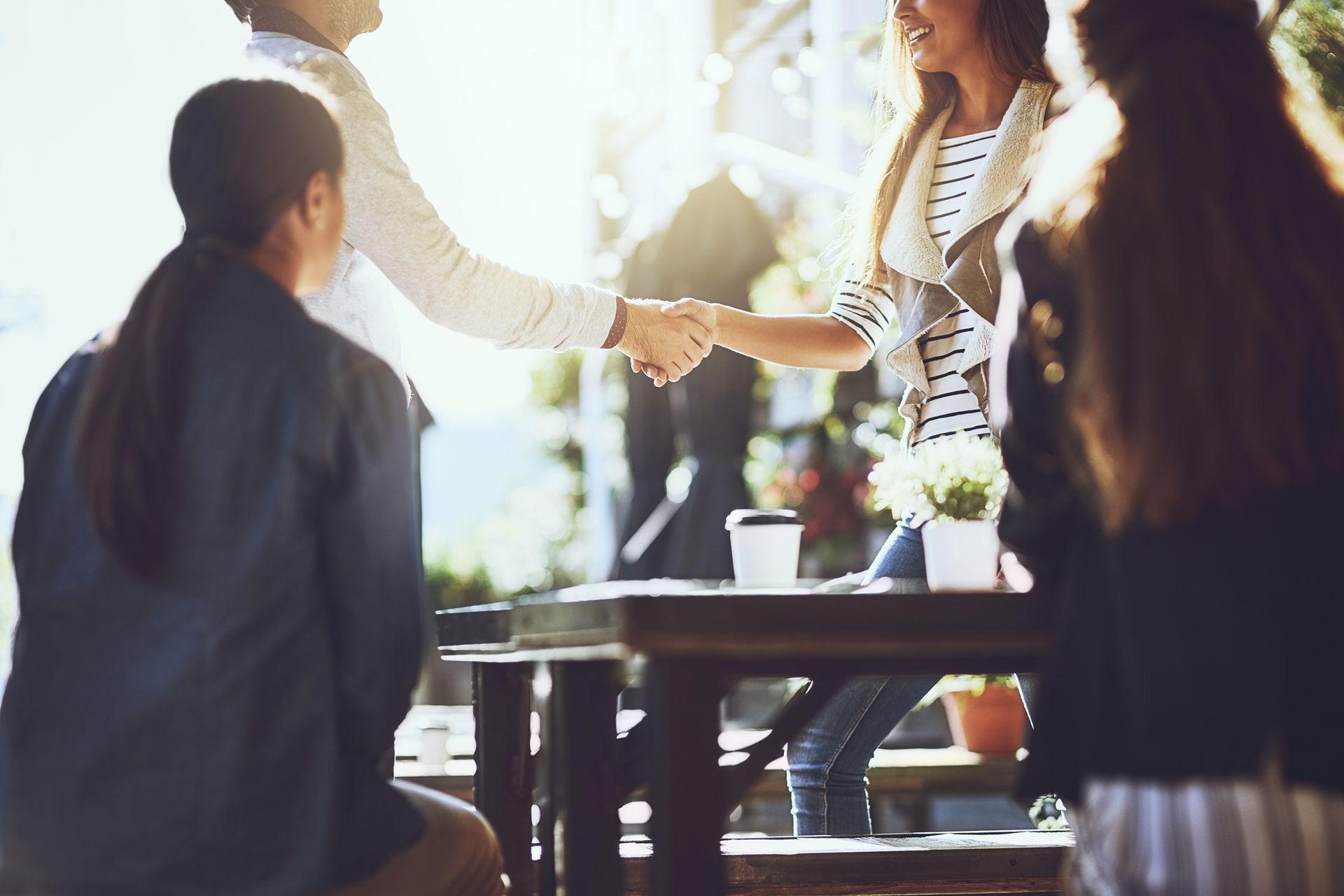 A group of people are sitting at a table shaking hands.