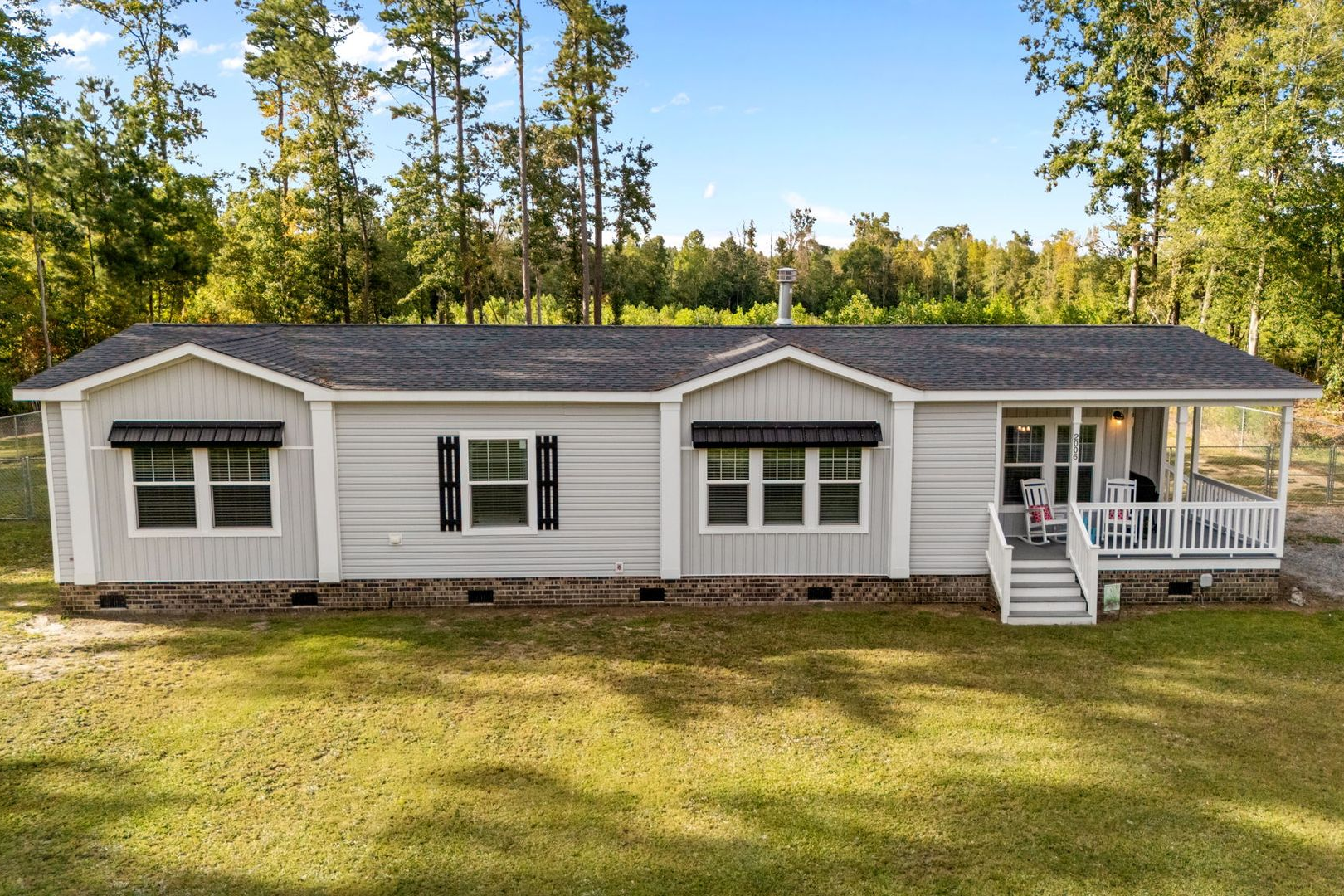 A large white apartment building with a brick wall and a balcony.