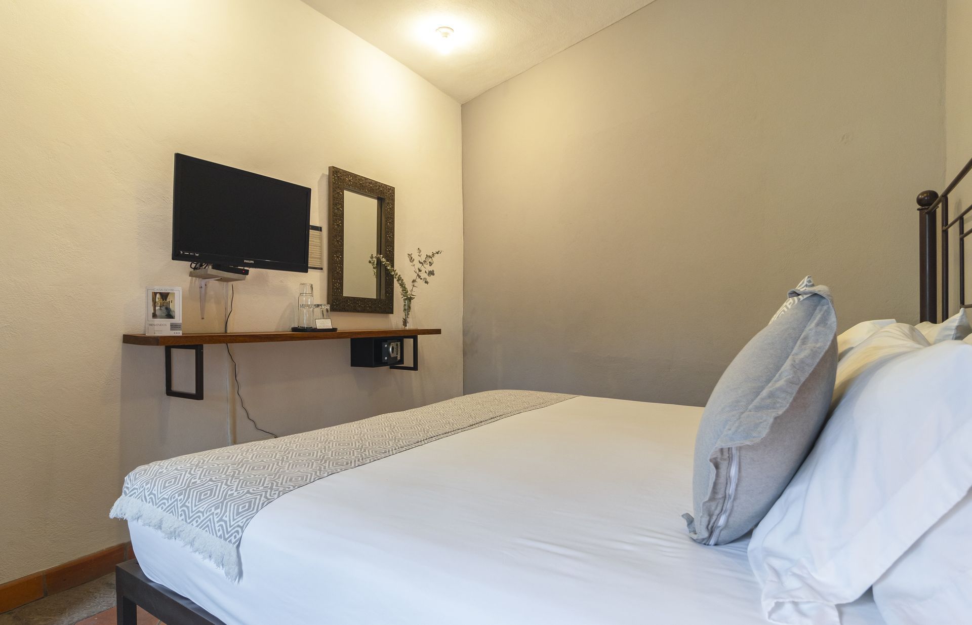 A bedroom with a king size bed and a flat screen tv on the wall.