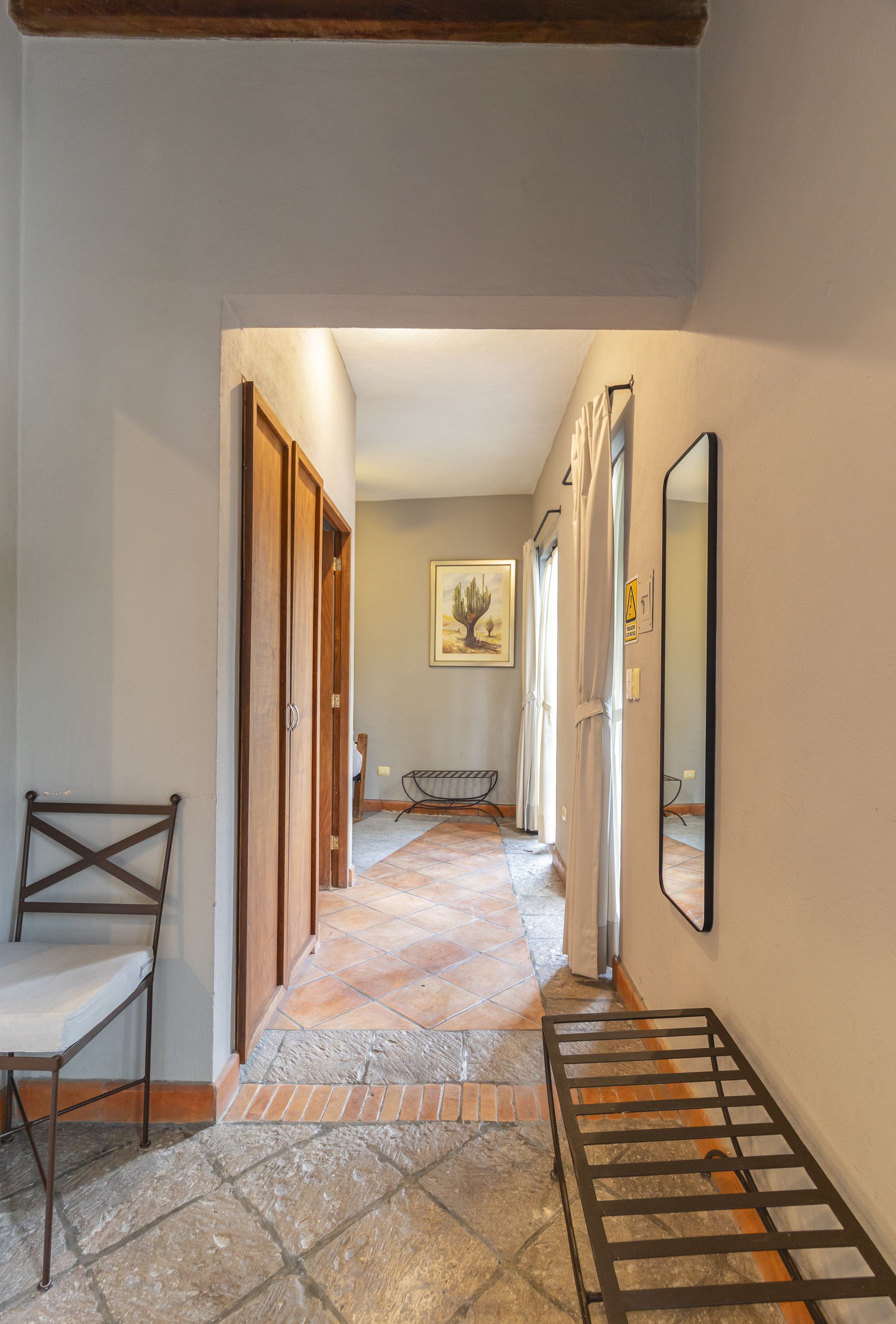 A hallway with a bench and a mirror on the wall.
