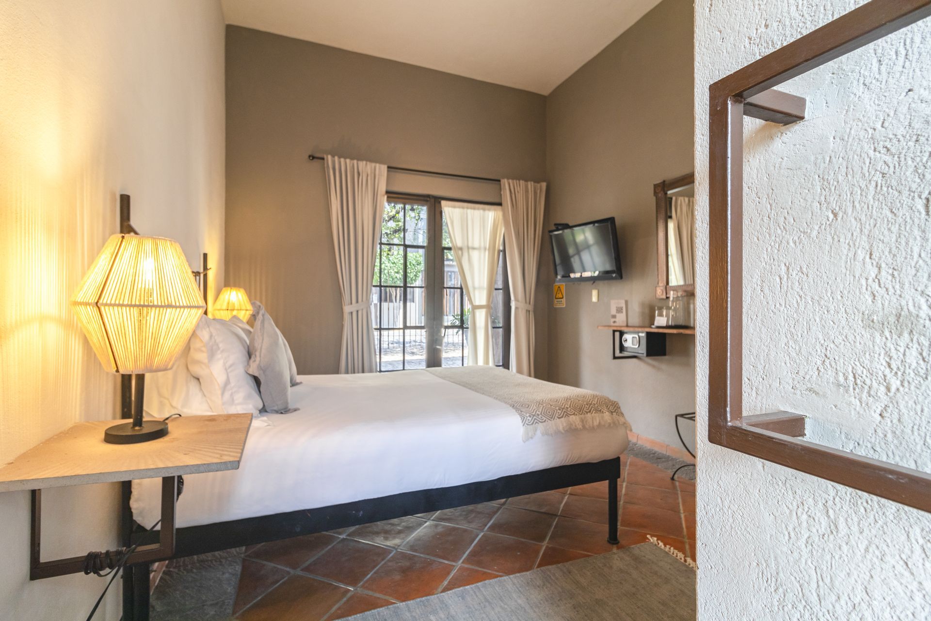 A bedroom with a king size bed , a television , a lamp , and a mirror.