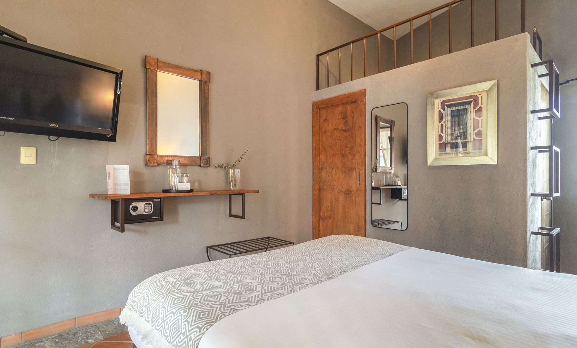 A bedroom with a bed , television , mirror and stairs.