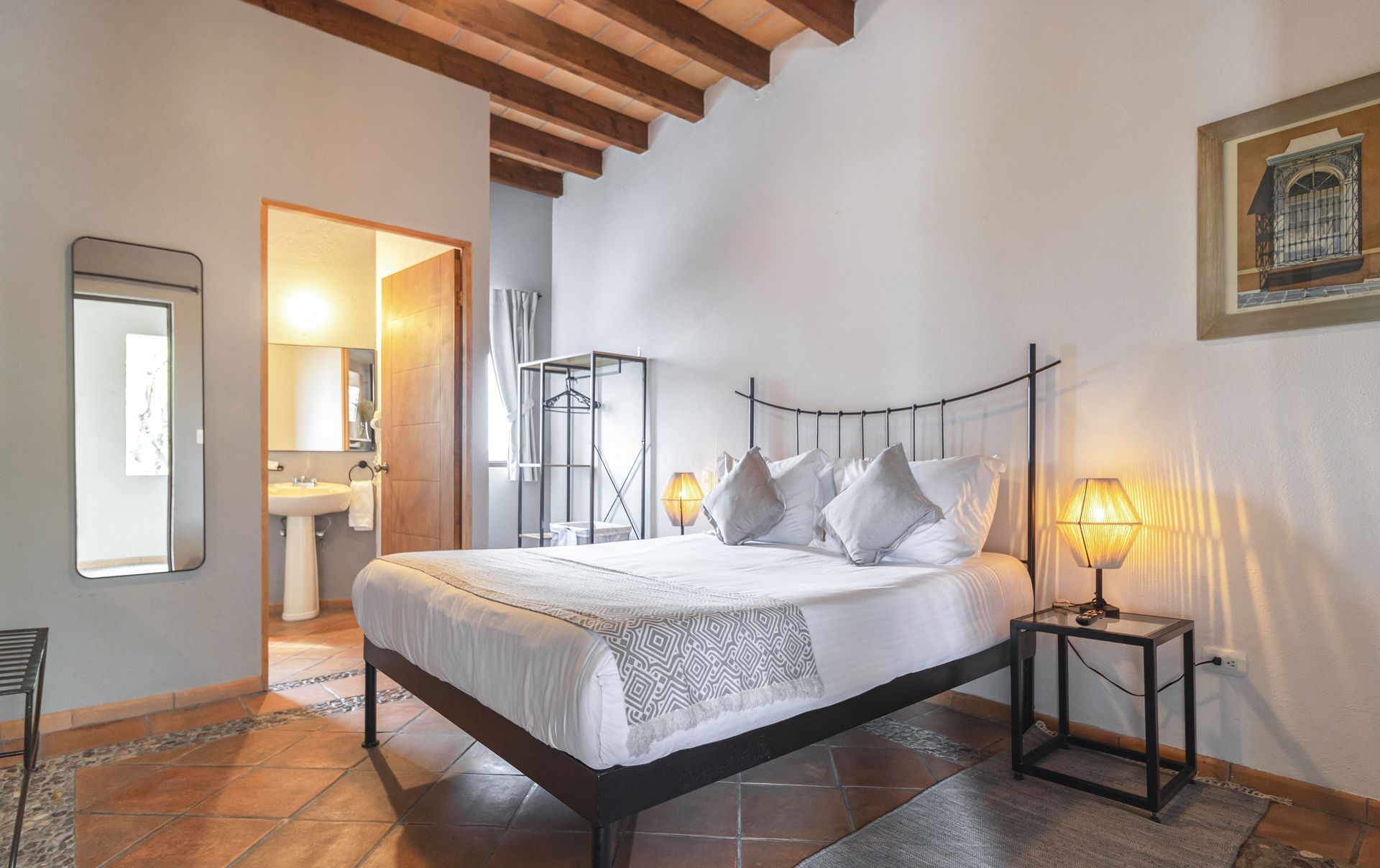 A bedroom with a bed , nightstand , mirror and bathroom.