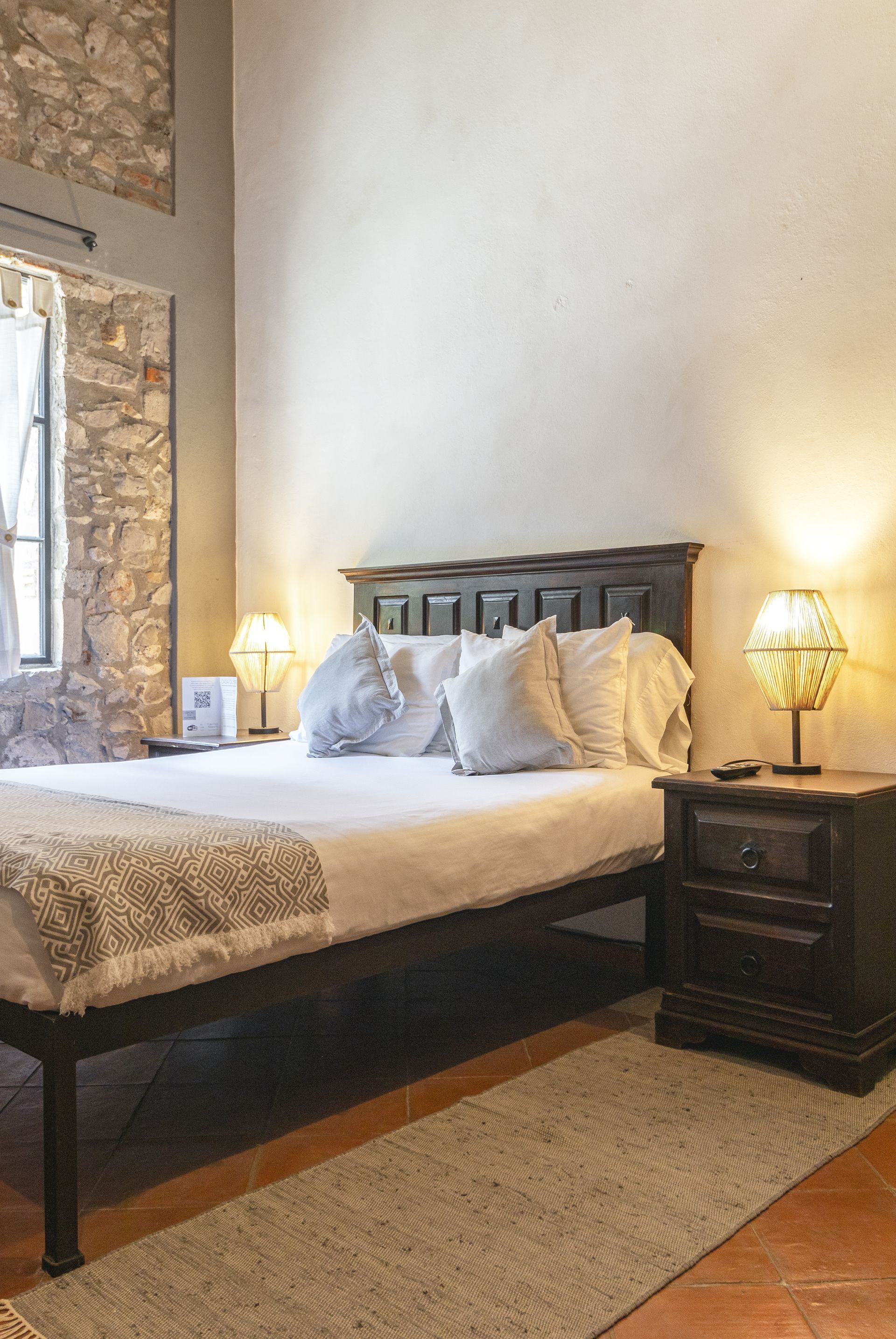 A bedroom with a bed , nightstand , and lamps.