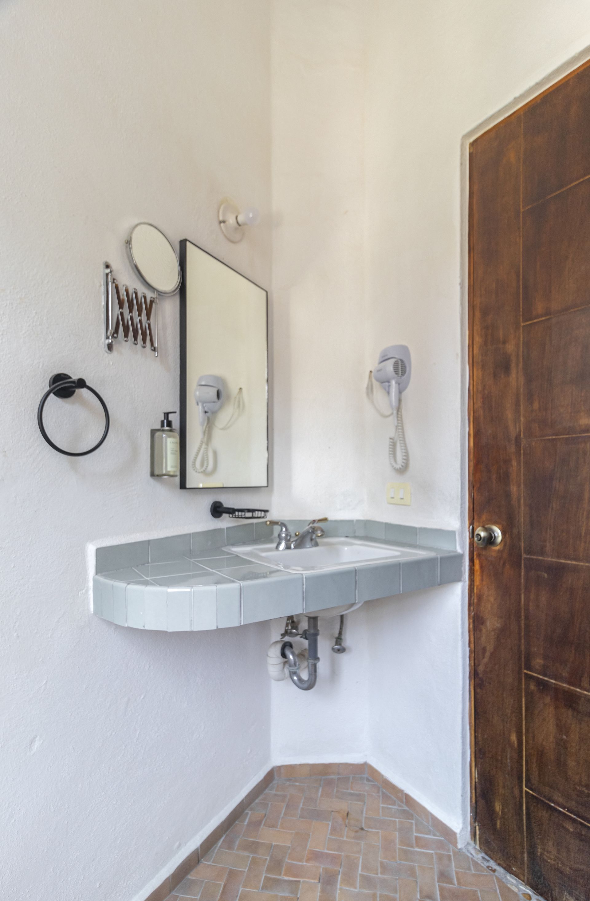 A bathroom with a sink , mirror and hair dryer.