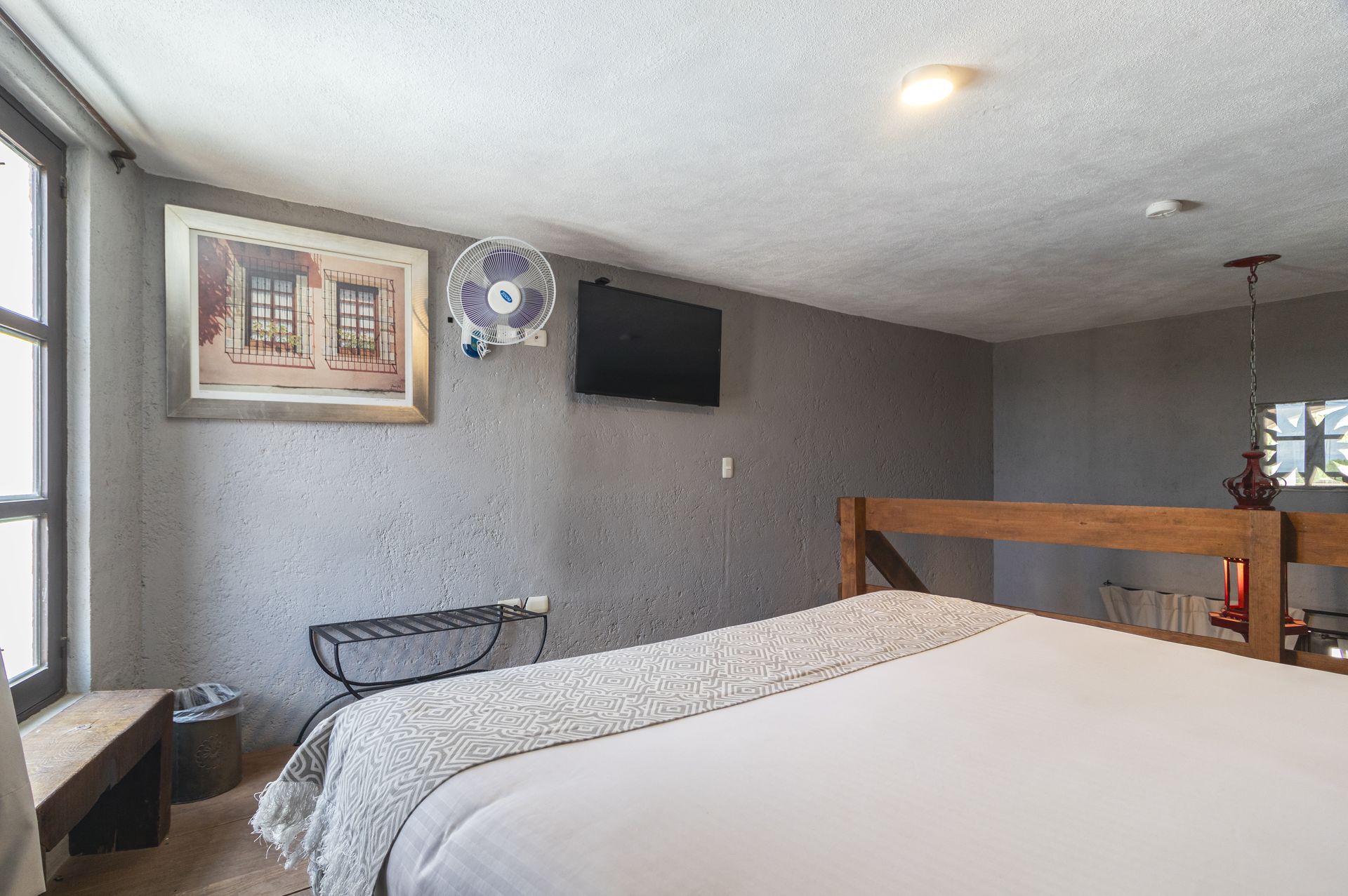 A bedroom with a bed , television , and fan.