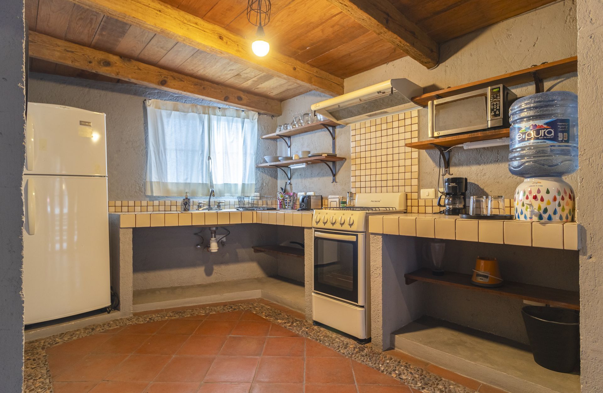 A kitchen with a refrigerator , stove , microwave and water cooler.