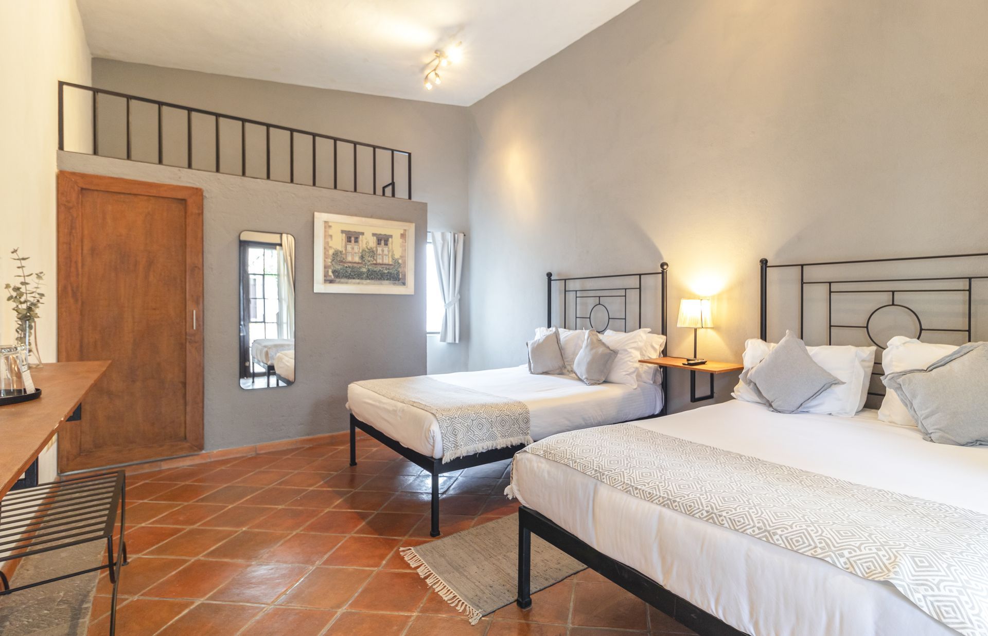 A bedroom with two beds , a desk and a mirror.