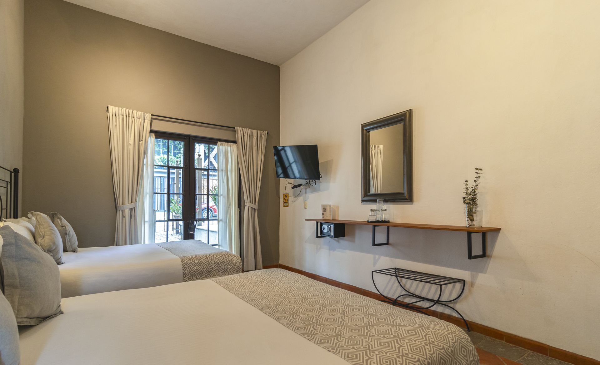 A hotel room with two beds , a television and a mirror.