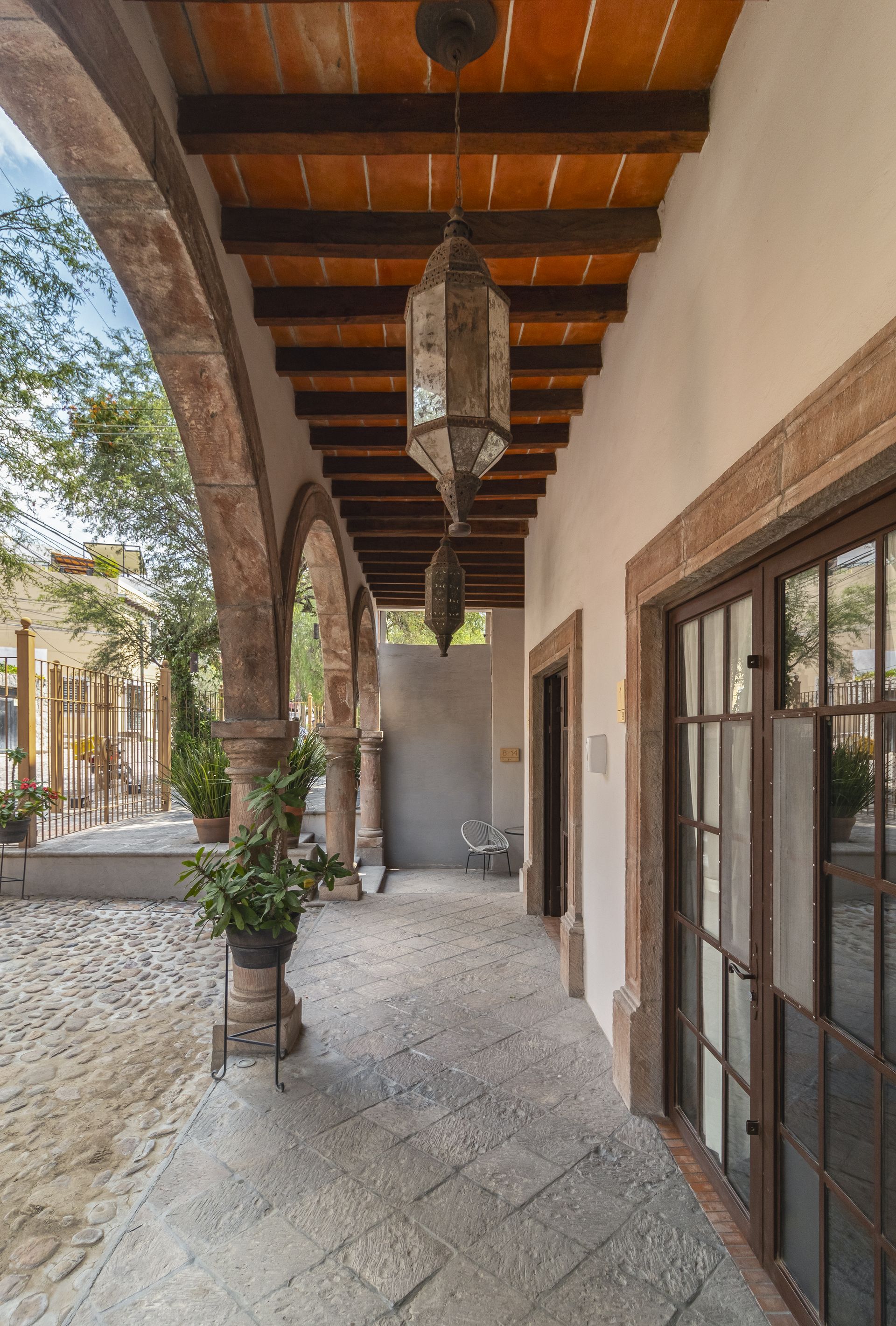 A long hallway with arches and a lantern hanging from the ceiling.
