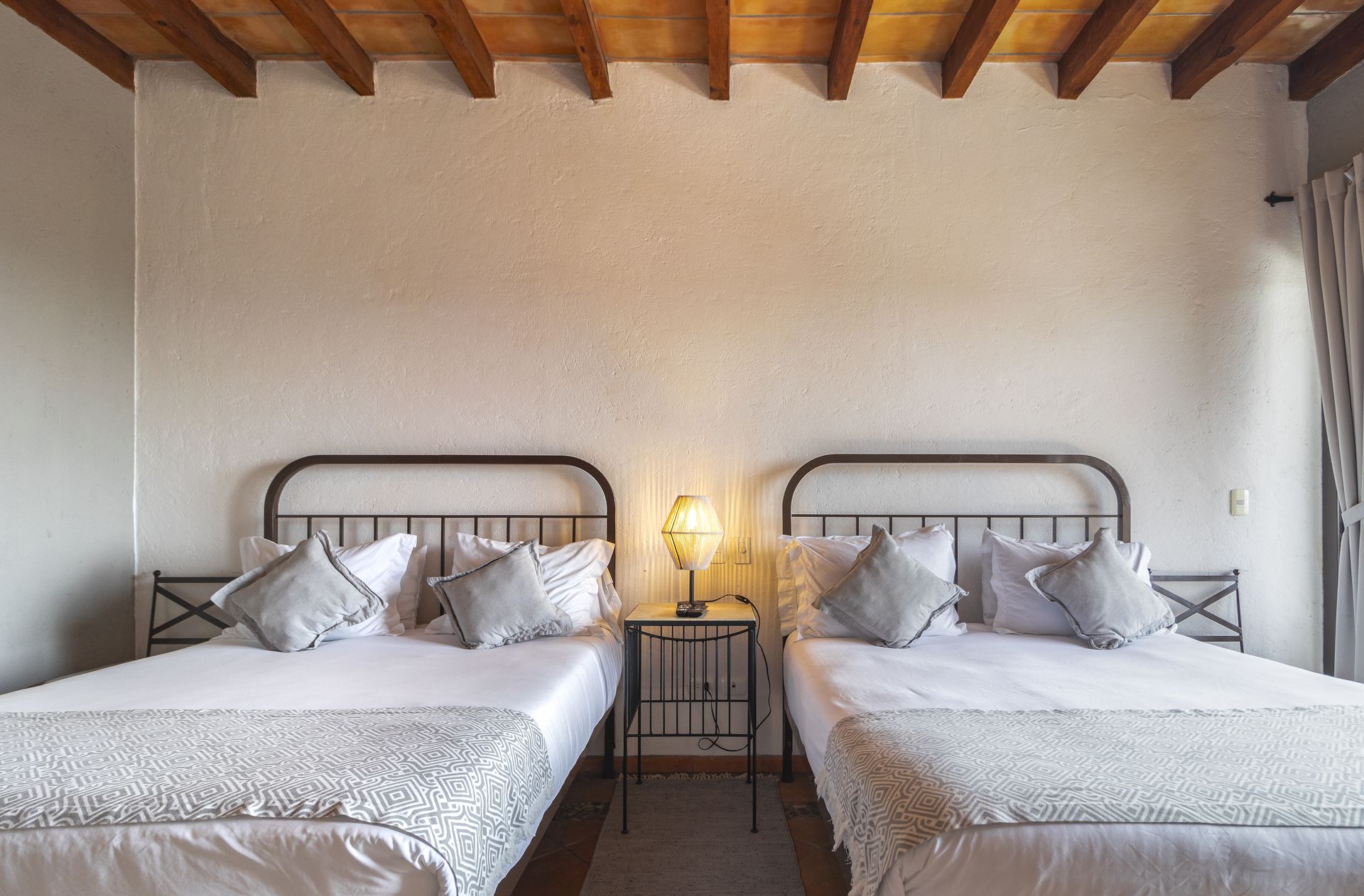 There are two beds in the room with a wooden ceiling.